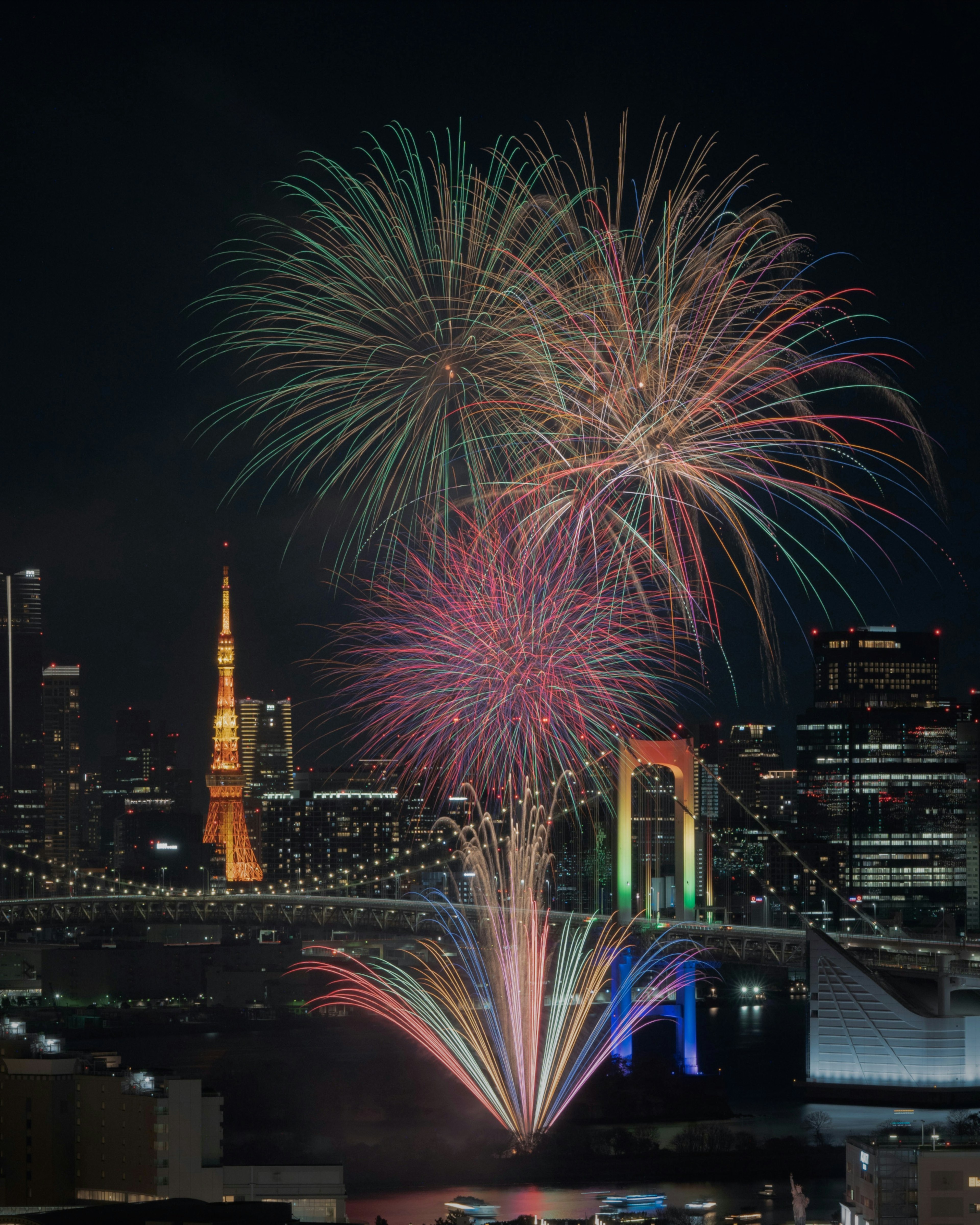 Colorful fireworks display over Tokyo skyline with the Rainbow Bridge visible