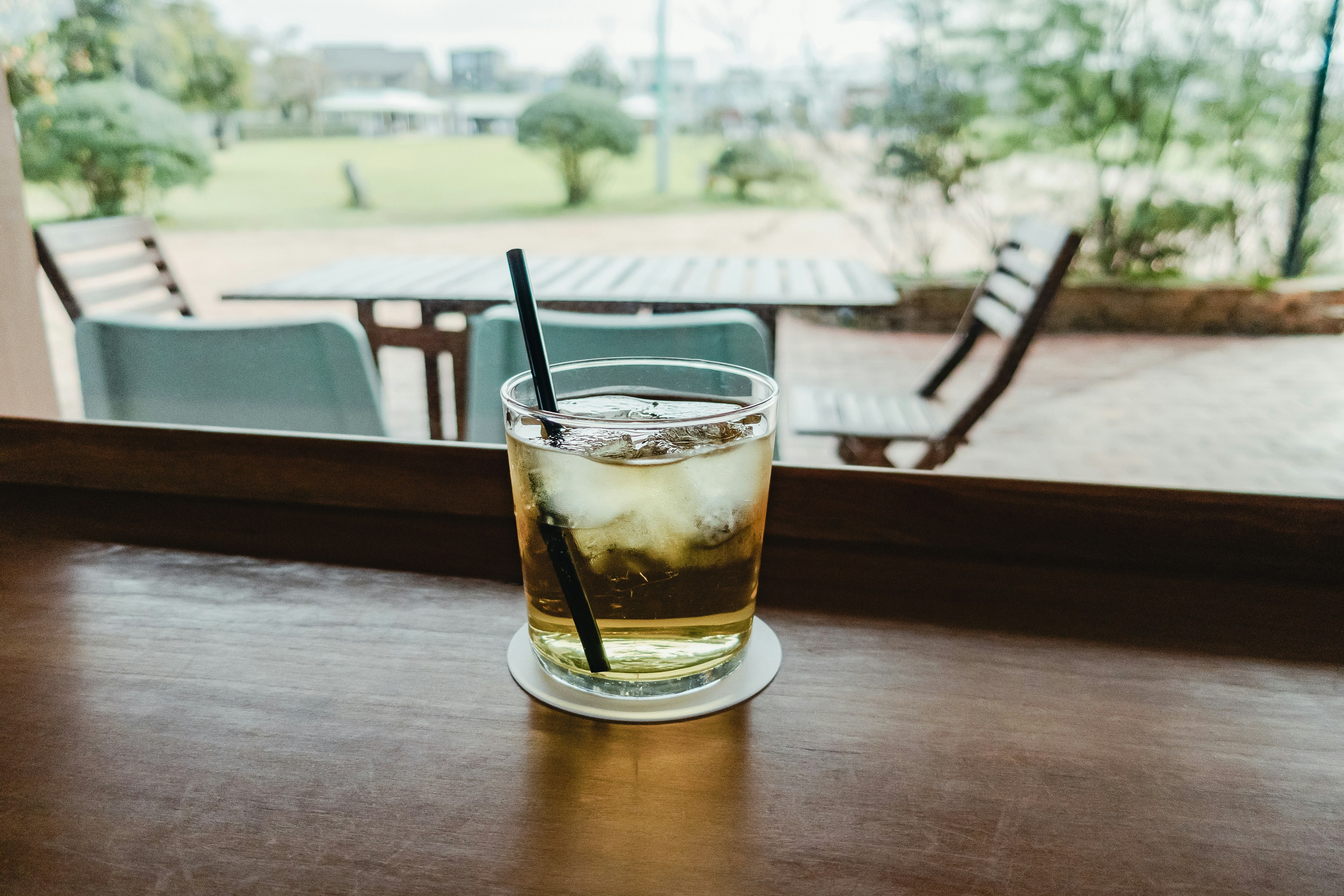 木桌上的冰飲料杯子與背景中的綠色花園