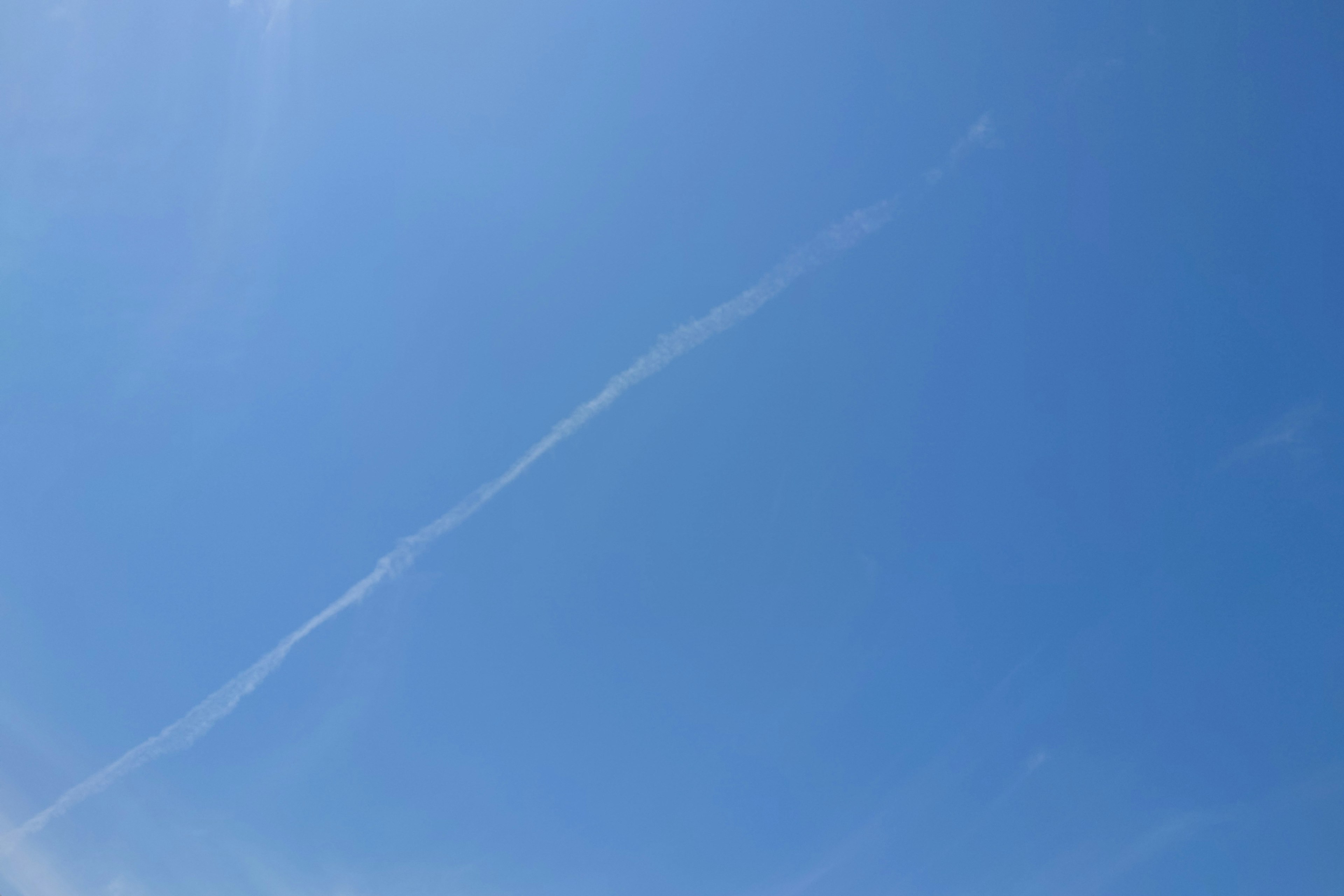 Langit biru cerah dengan jejak putih yang membentang