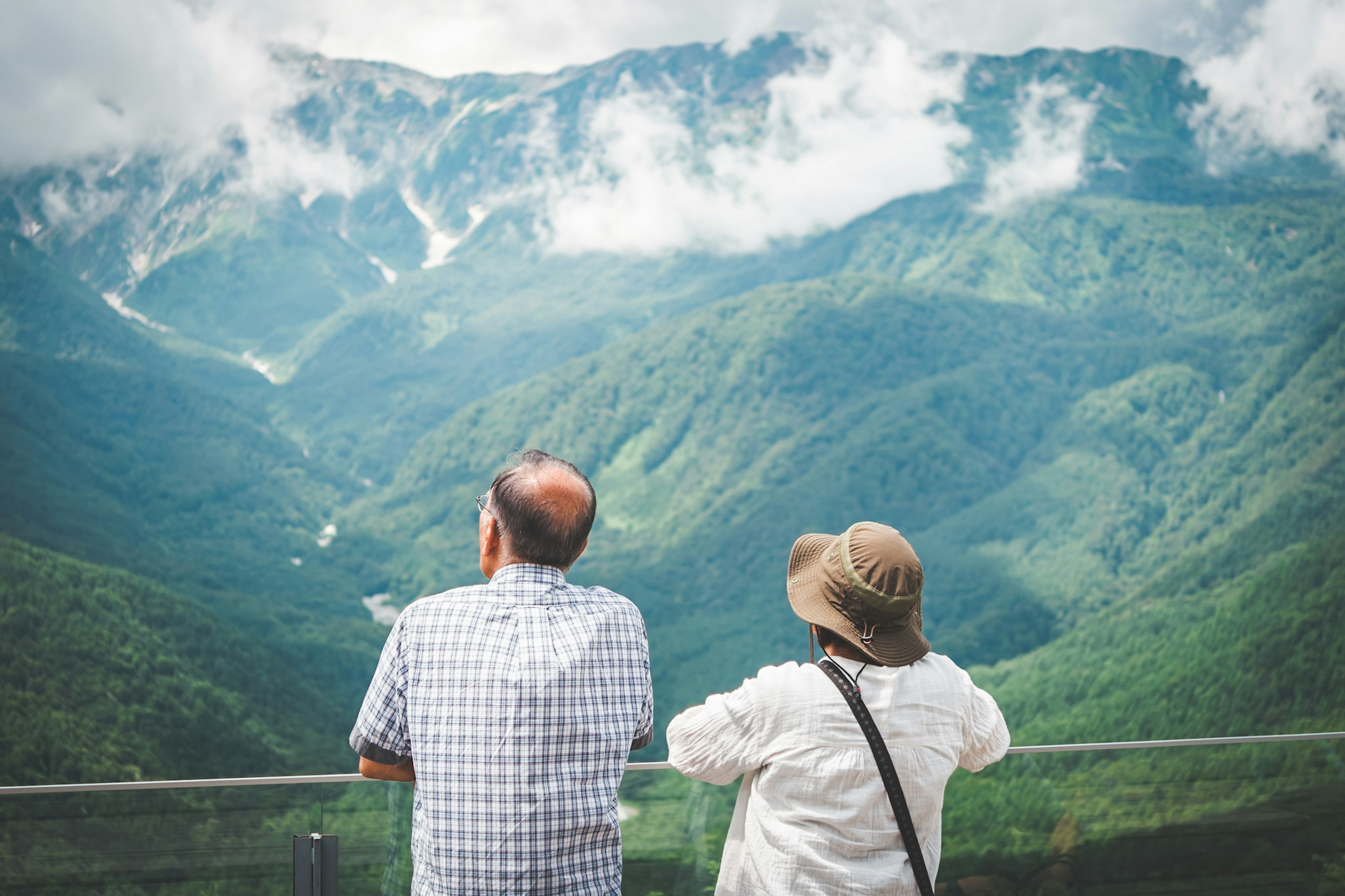 山の景色を眺める二人のシニアカップル