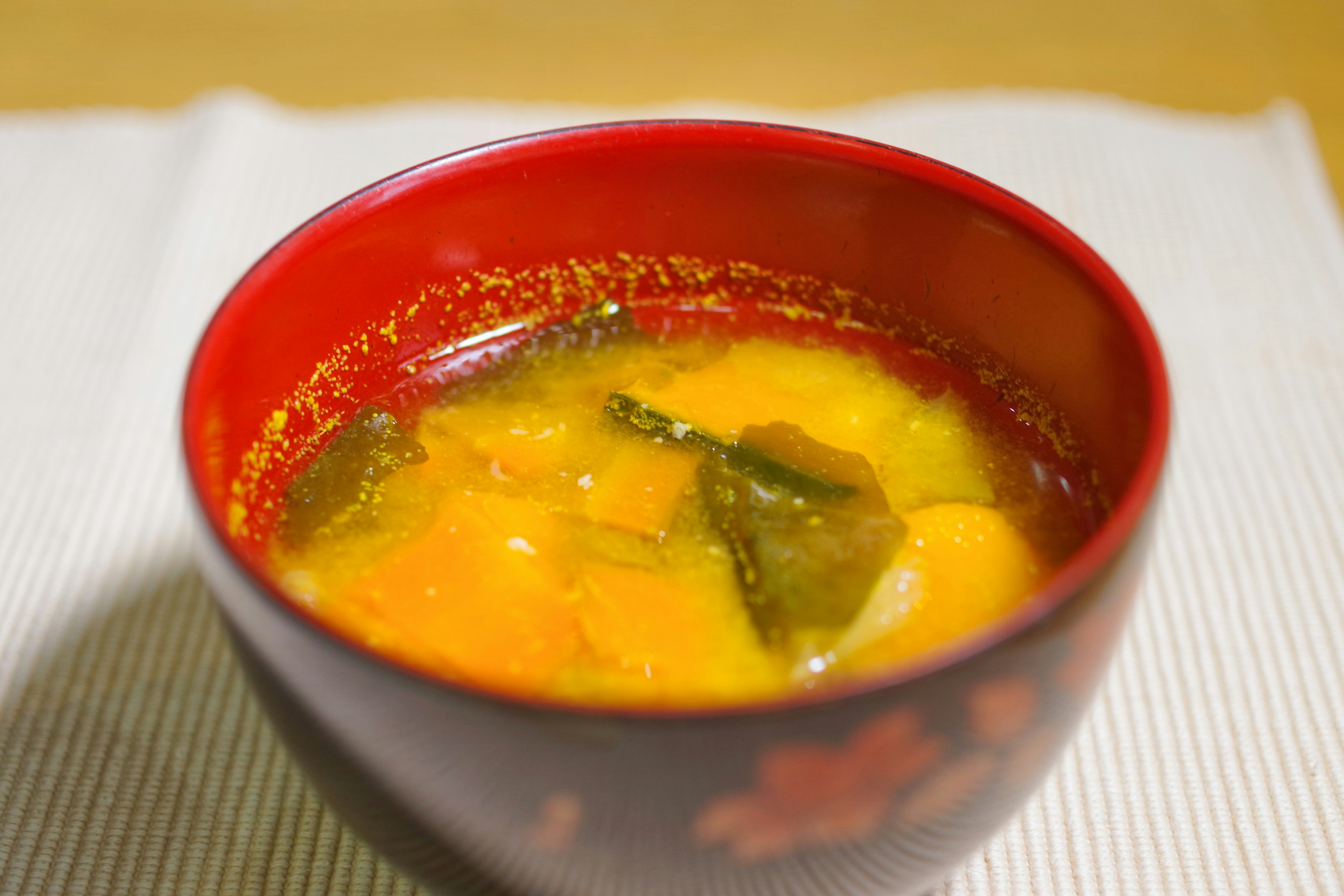 Warm soup with vegetables in a red bowl