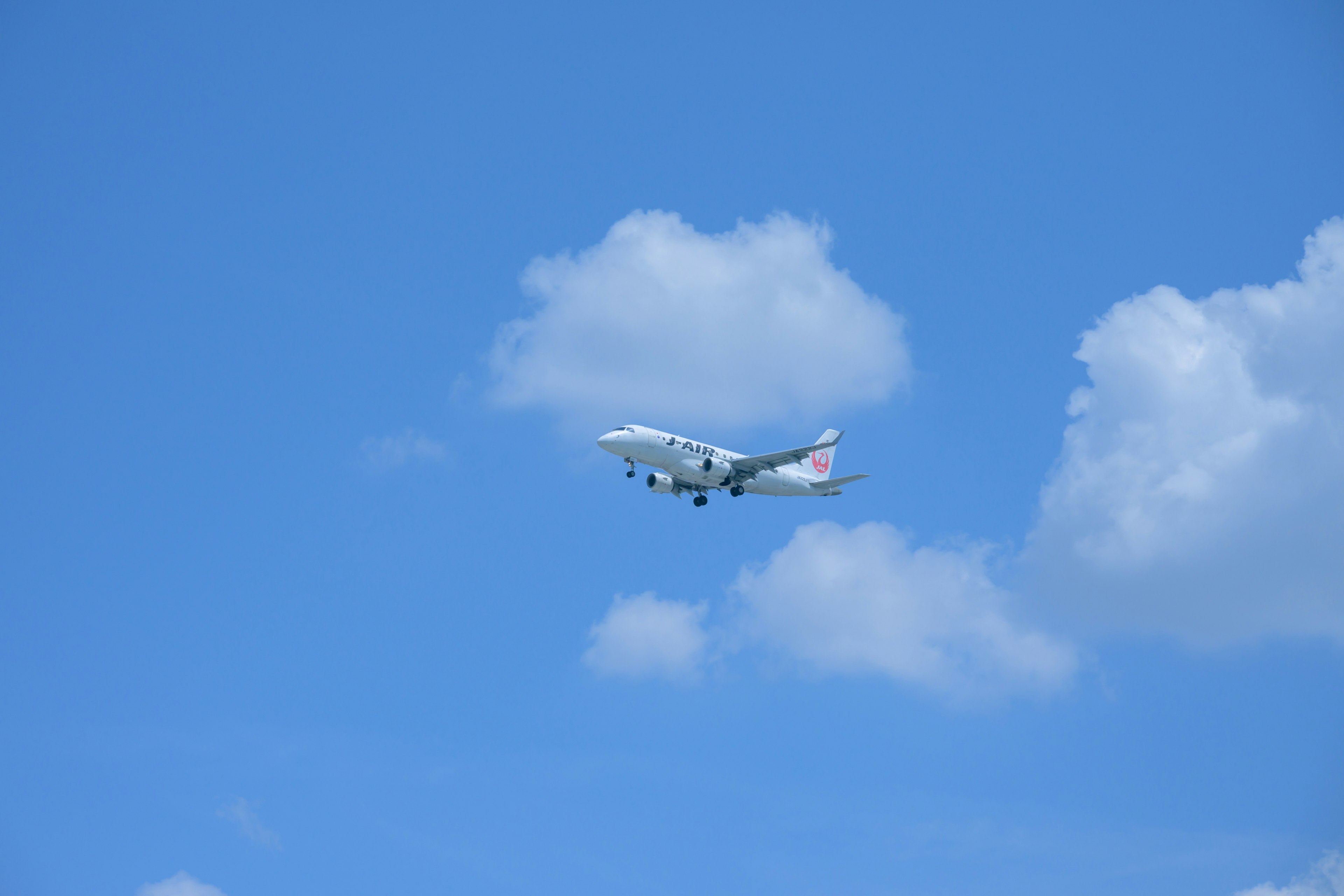 Avión volando en un cielo azul claro con nubes blancas