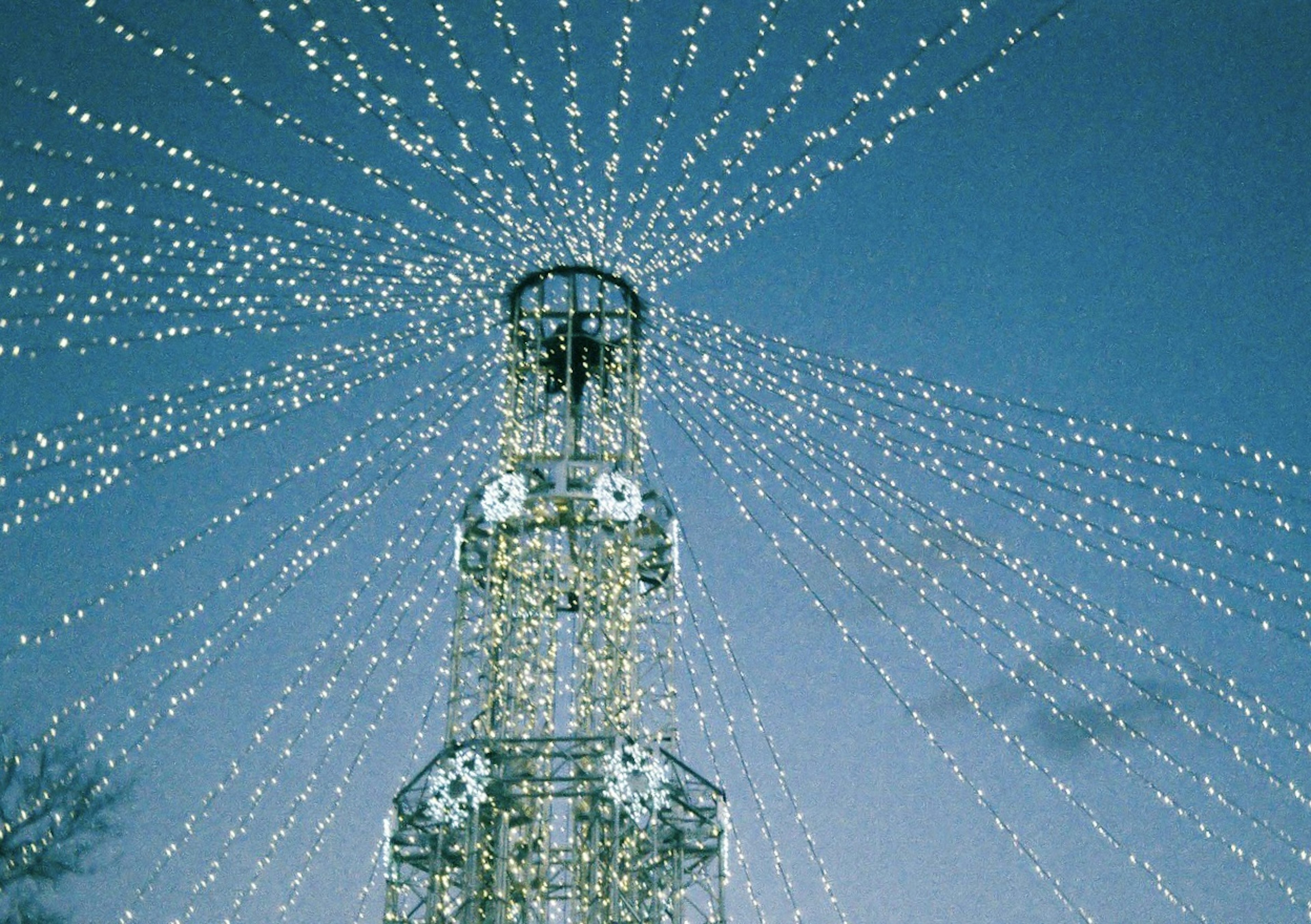 Illumination tower radiating light beams against a blue sky