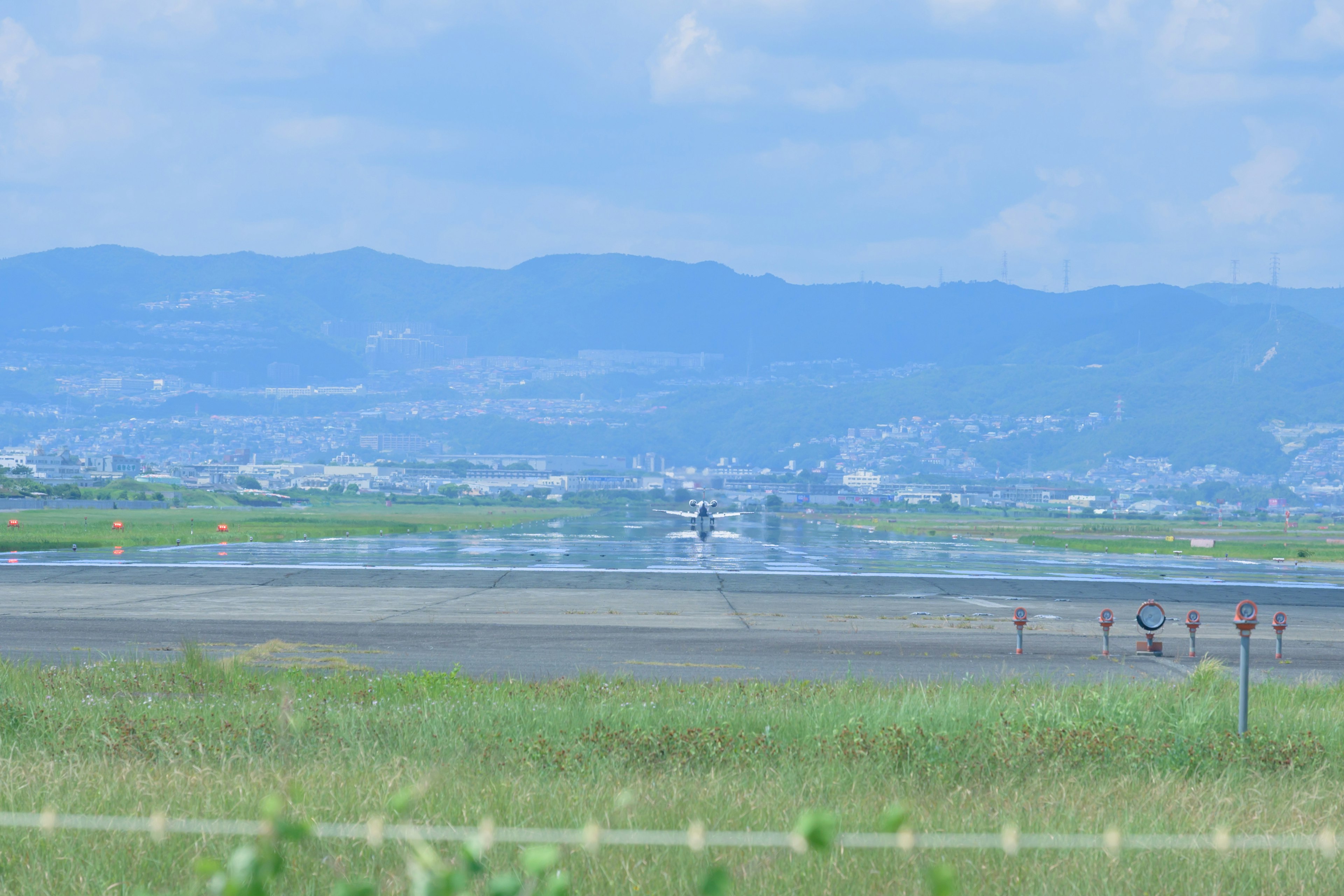 Pista di aeroporto con prati verdi e montagne lontane sotto un cielo blu