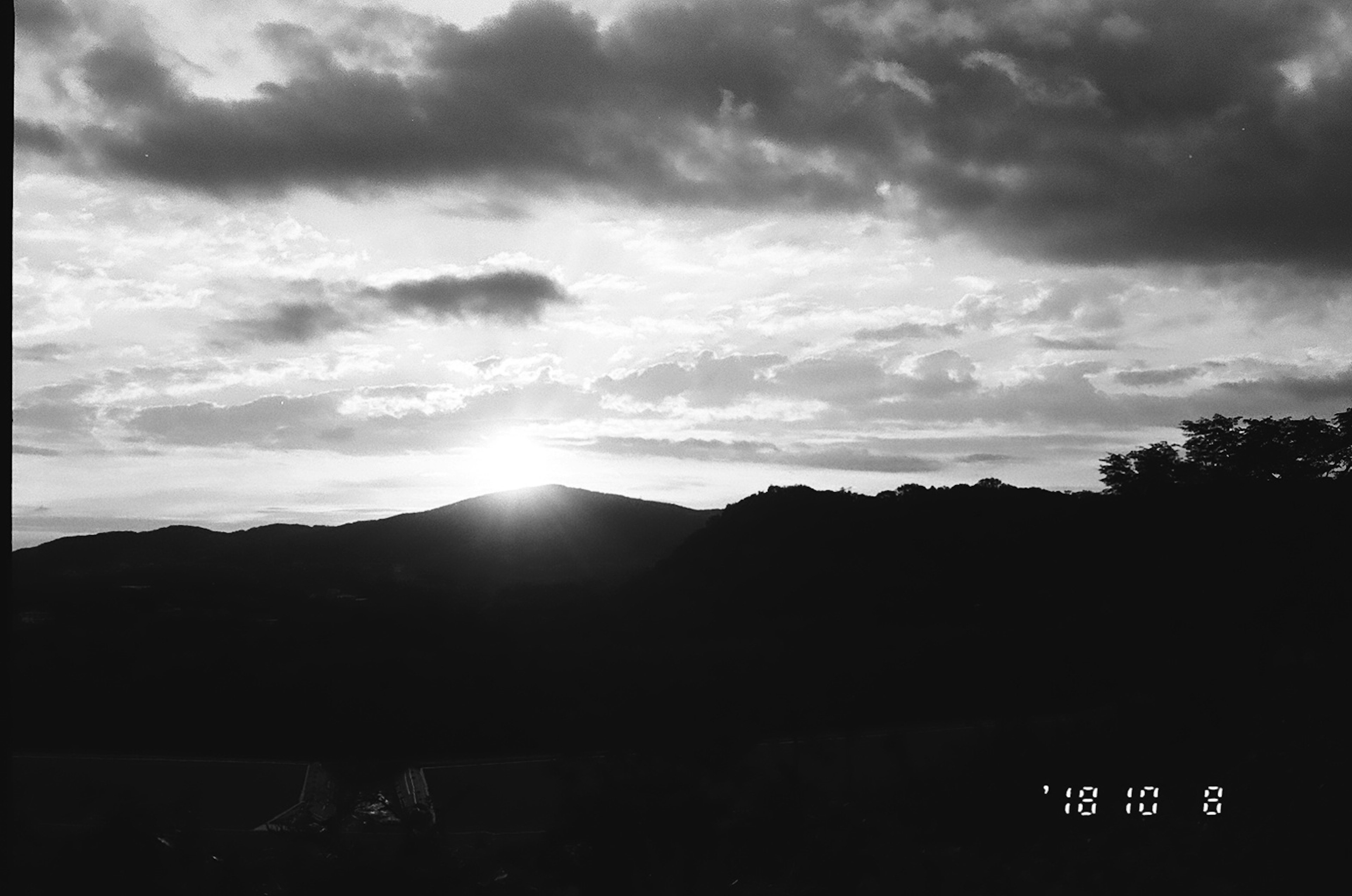 Paysage en noir et blanc avec un soleil couchant et des montagnes