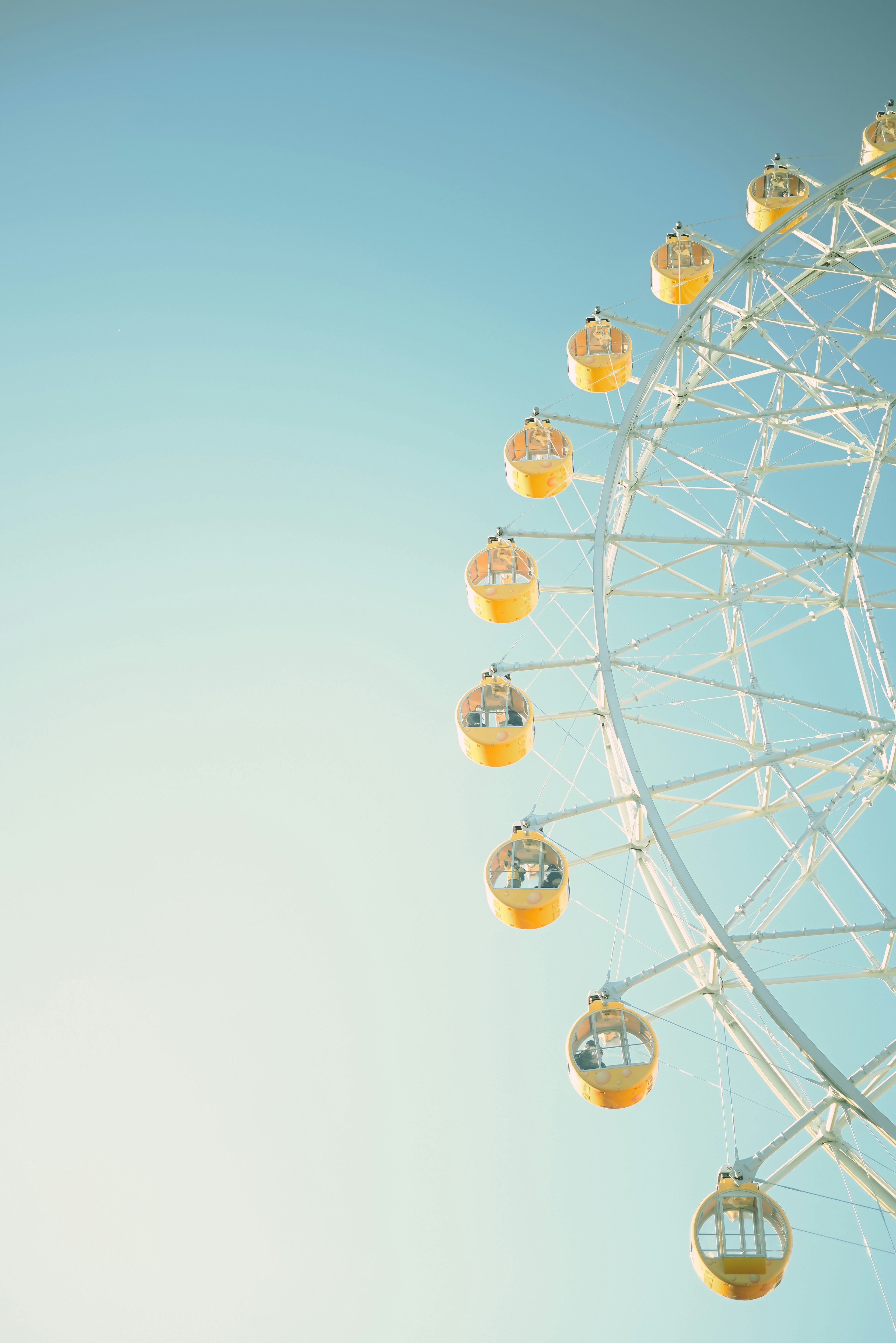 Partie d'une grande roue avec des capsules jaunes sous un ciel bleu