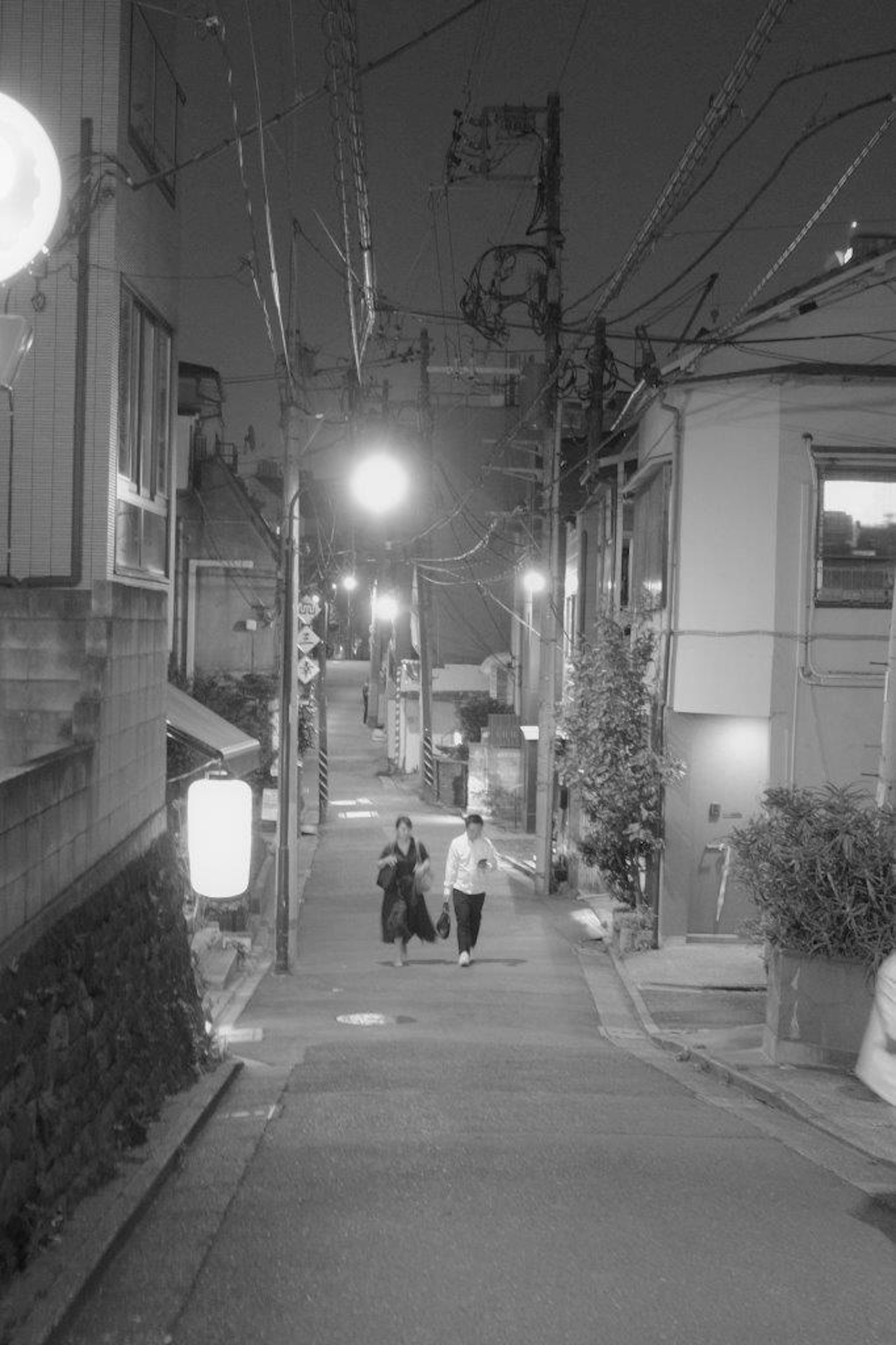 Personnes marchant dans une rue tranquille la nuit avec des lampadaires