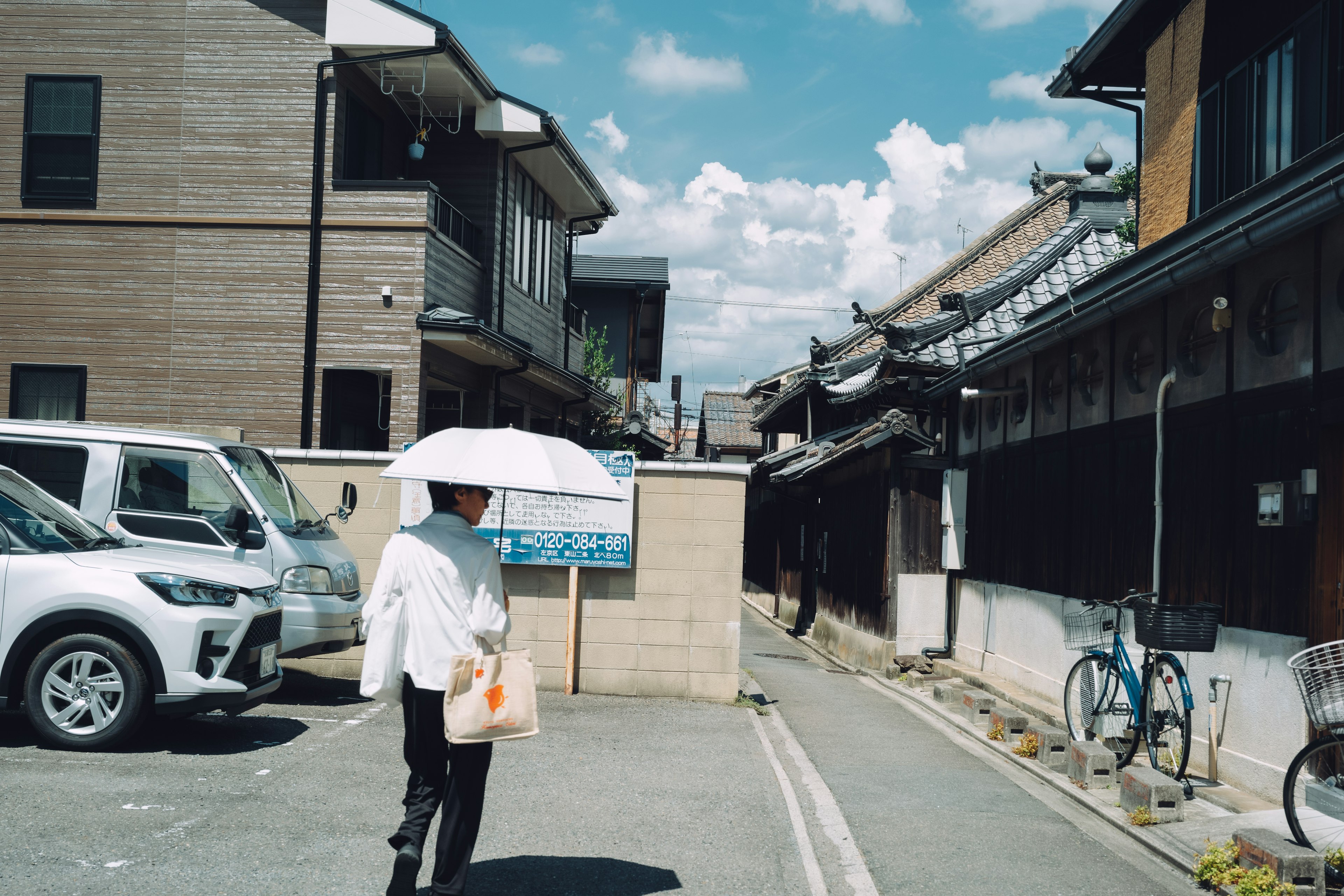 A person walking around a corner with an umbrella on a sunny day