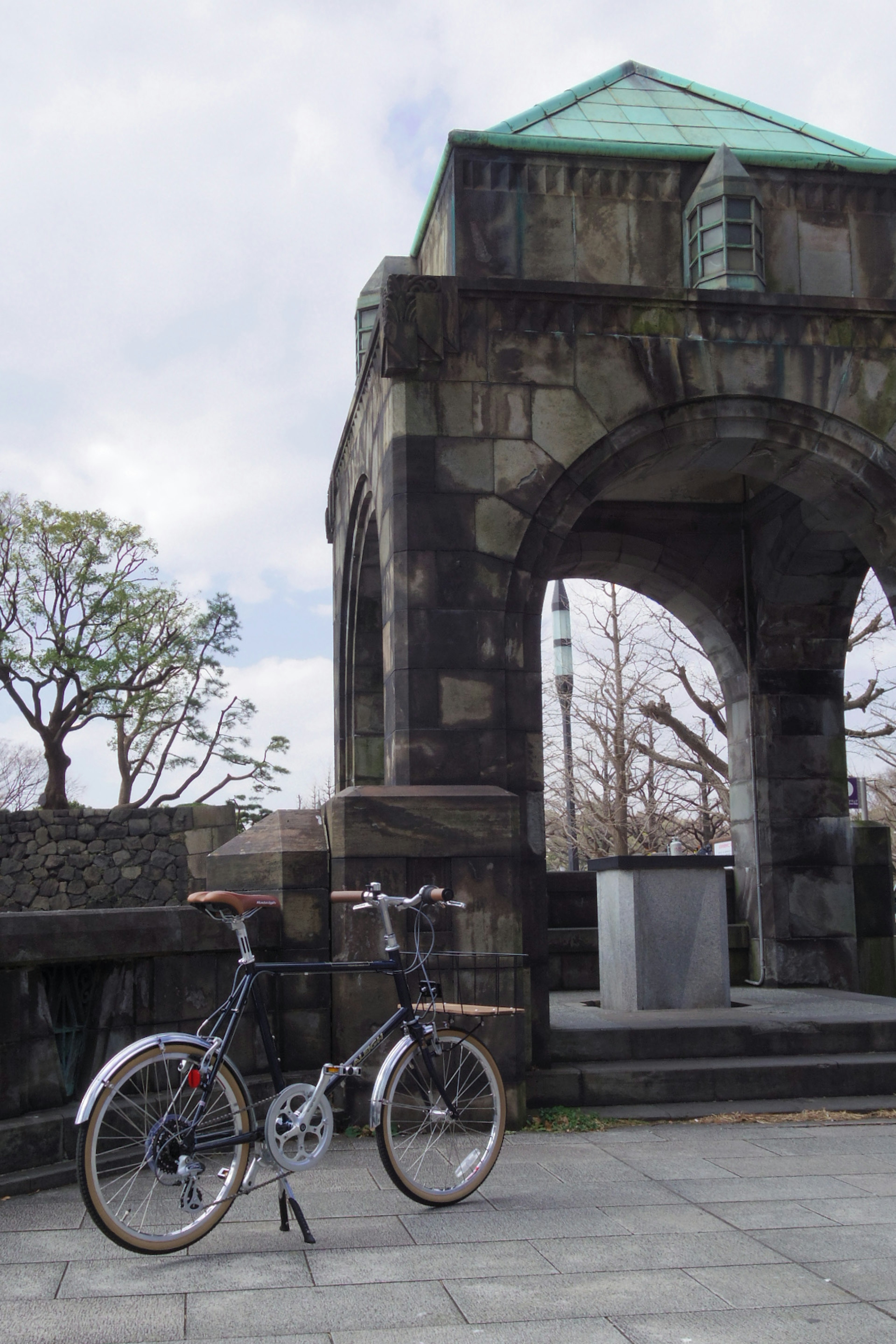 Fahrrad unter einem Steinbogen mit Bäumen im Hintergrund geparkt