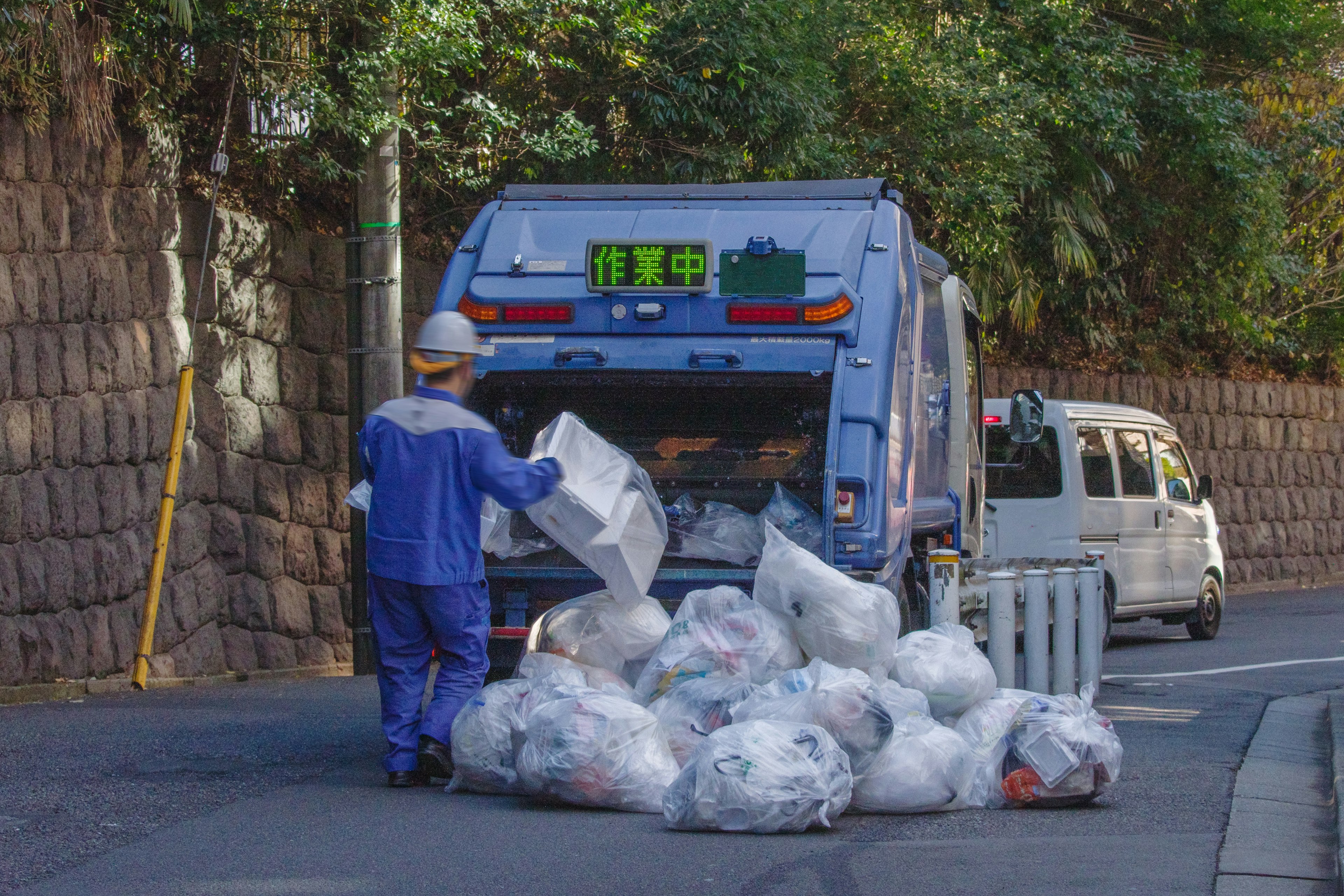 Un camion poubelle bleu ramassant des déchets dans une rue de la ville