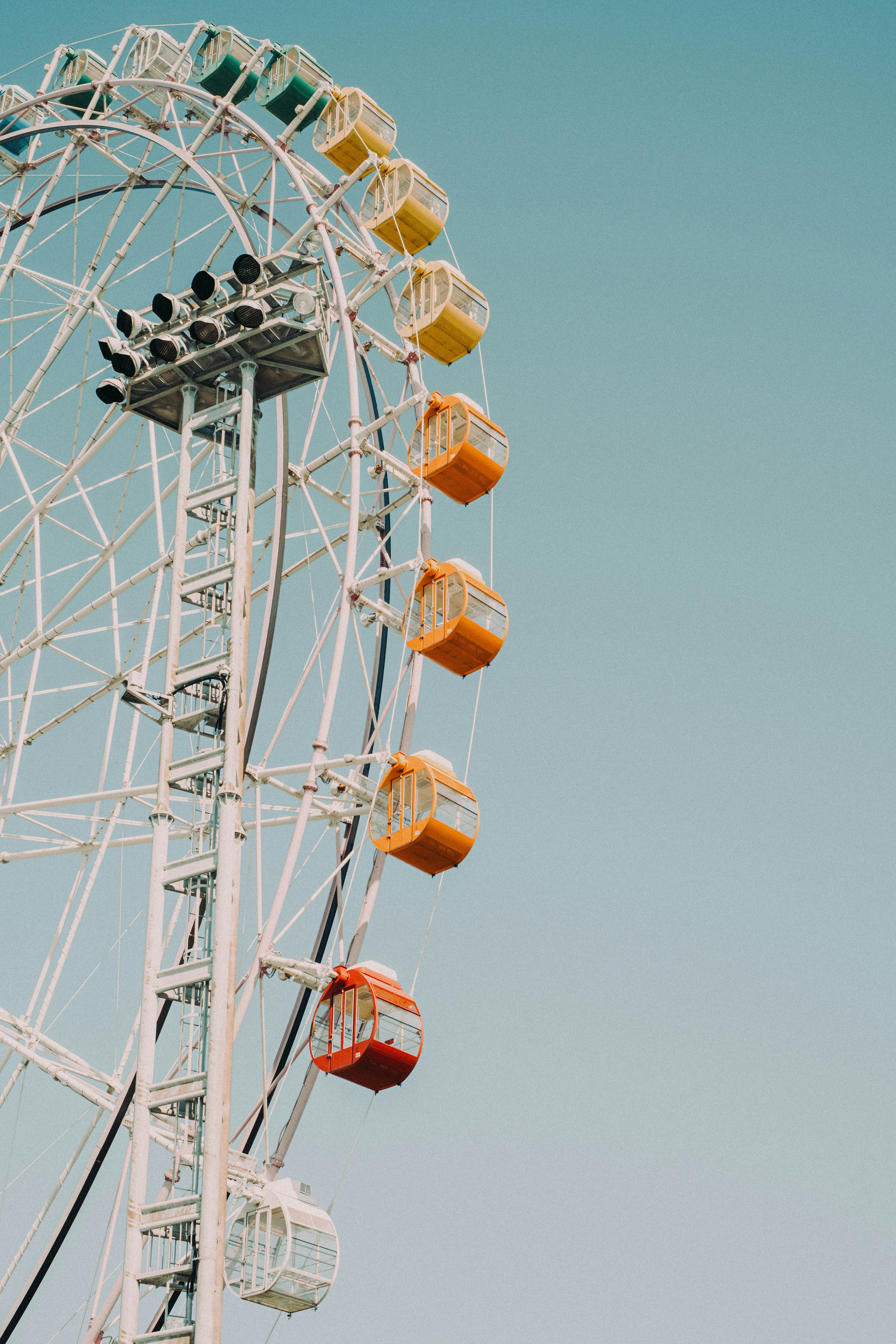 Side view of a Ferris wheel with colorful cabins against a blue sky