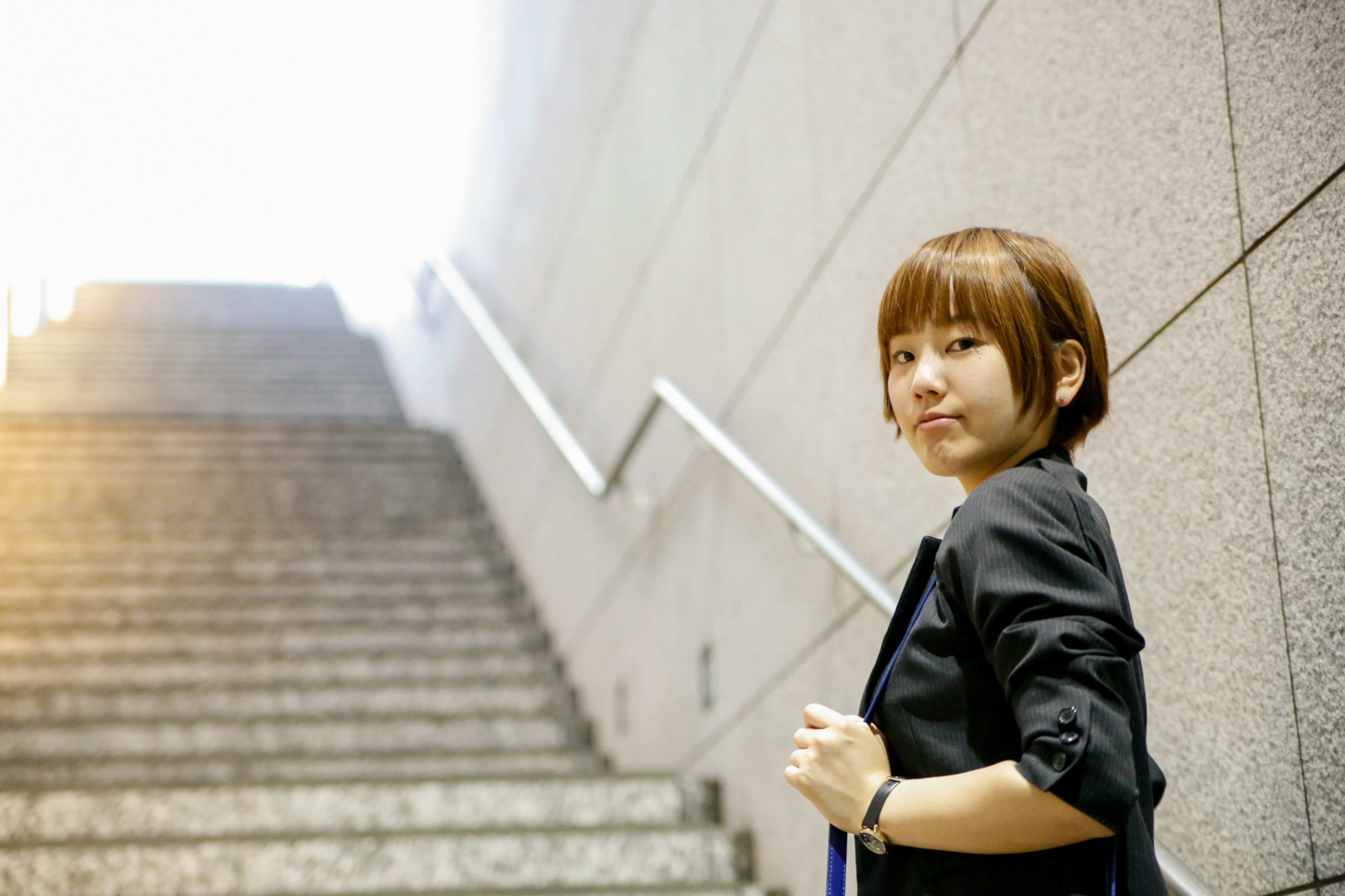 Portrait of a young woman standing near stairs with a confident smile