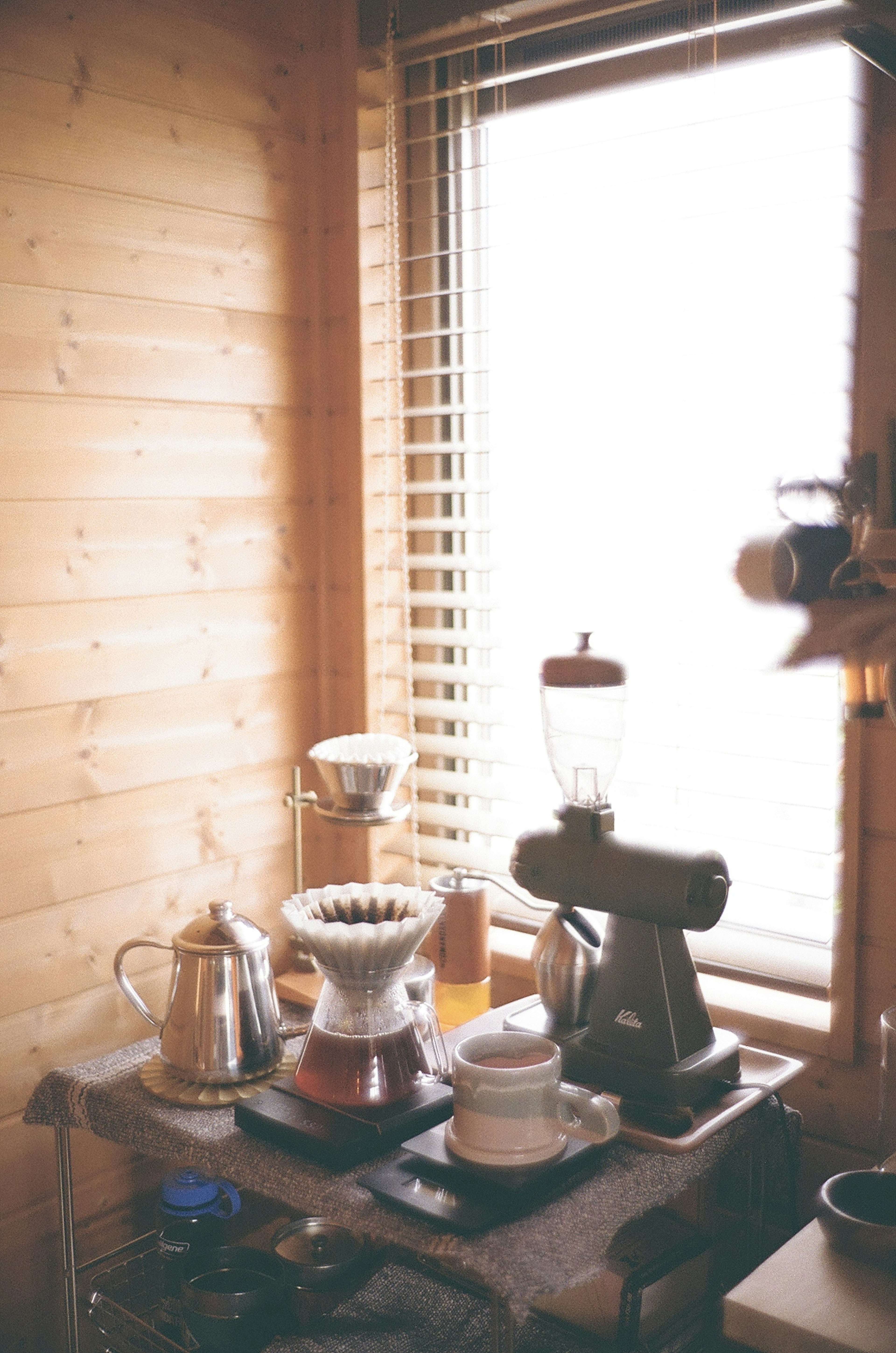 A cozy wooden room with coffee equipment arranged by a window