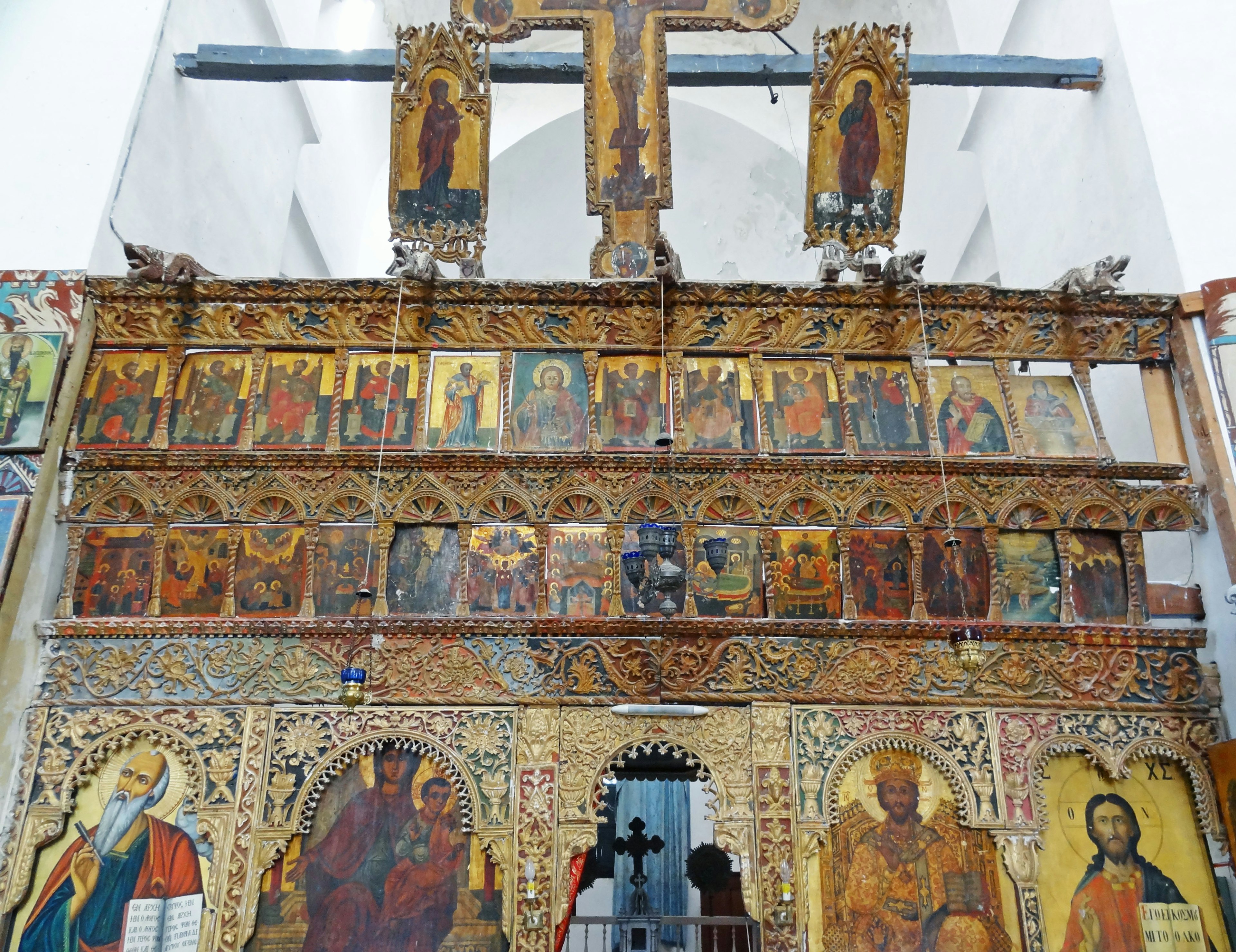 Wooden altar with vibrant icons and religious paintings featuring a prominent cross at the top