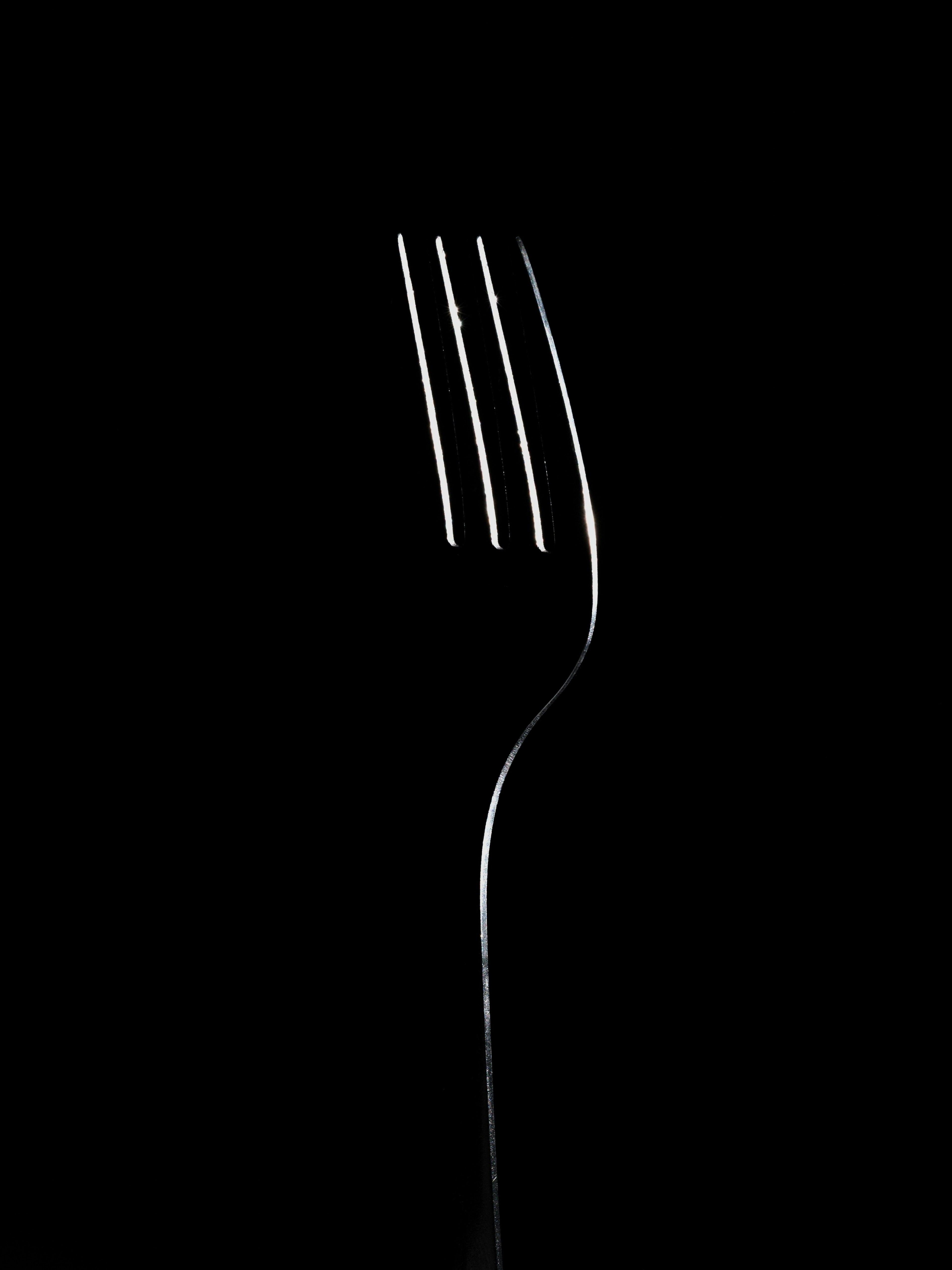 A fork with three prongs shining against a black background