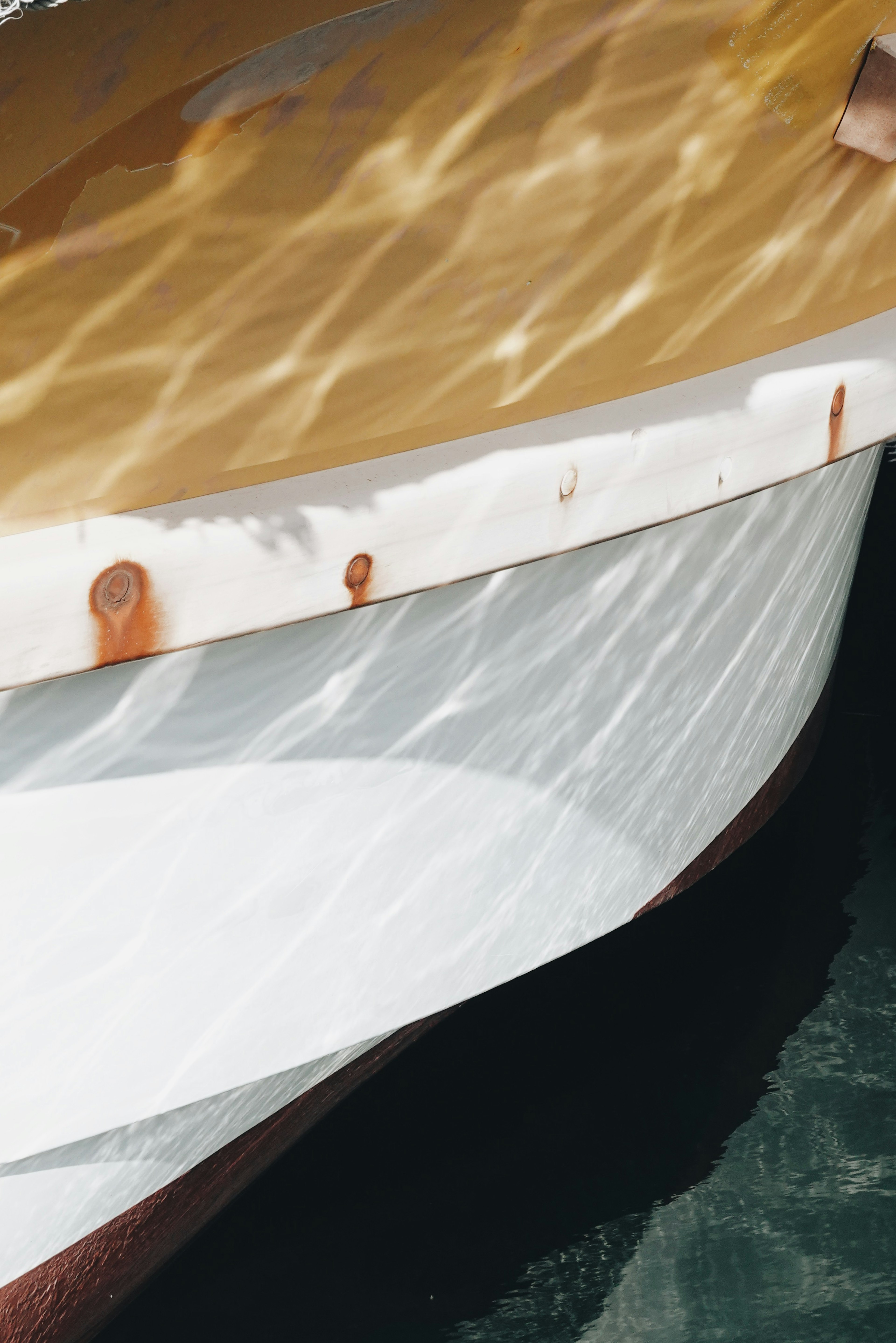 Borde de barco reflejándose en la superficie del agua con ondas