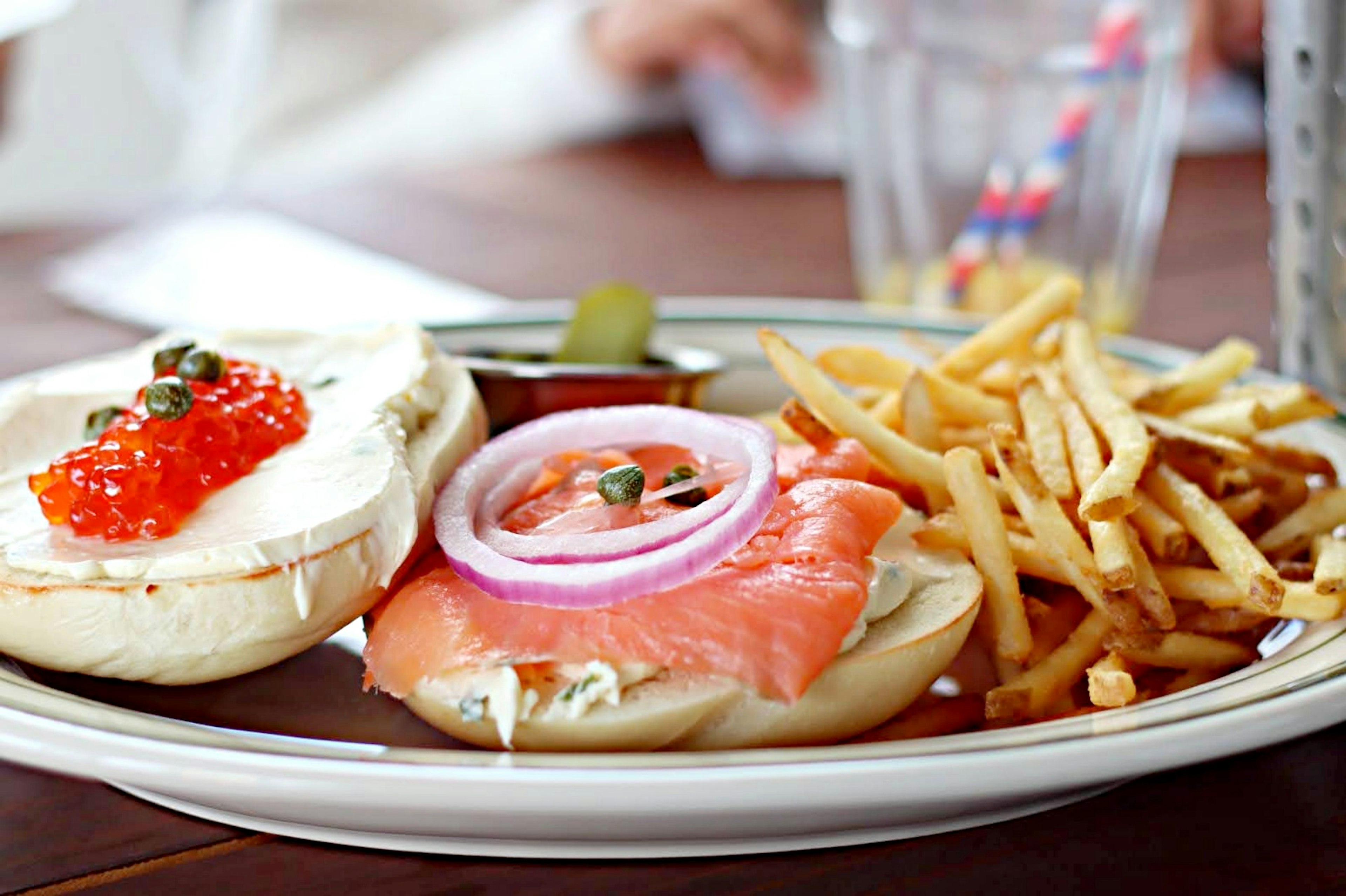 Sandwich con bagel, salmone affumicato e formaggio cremoso servito con patatine fritte