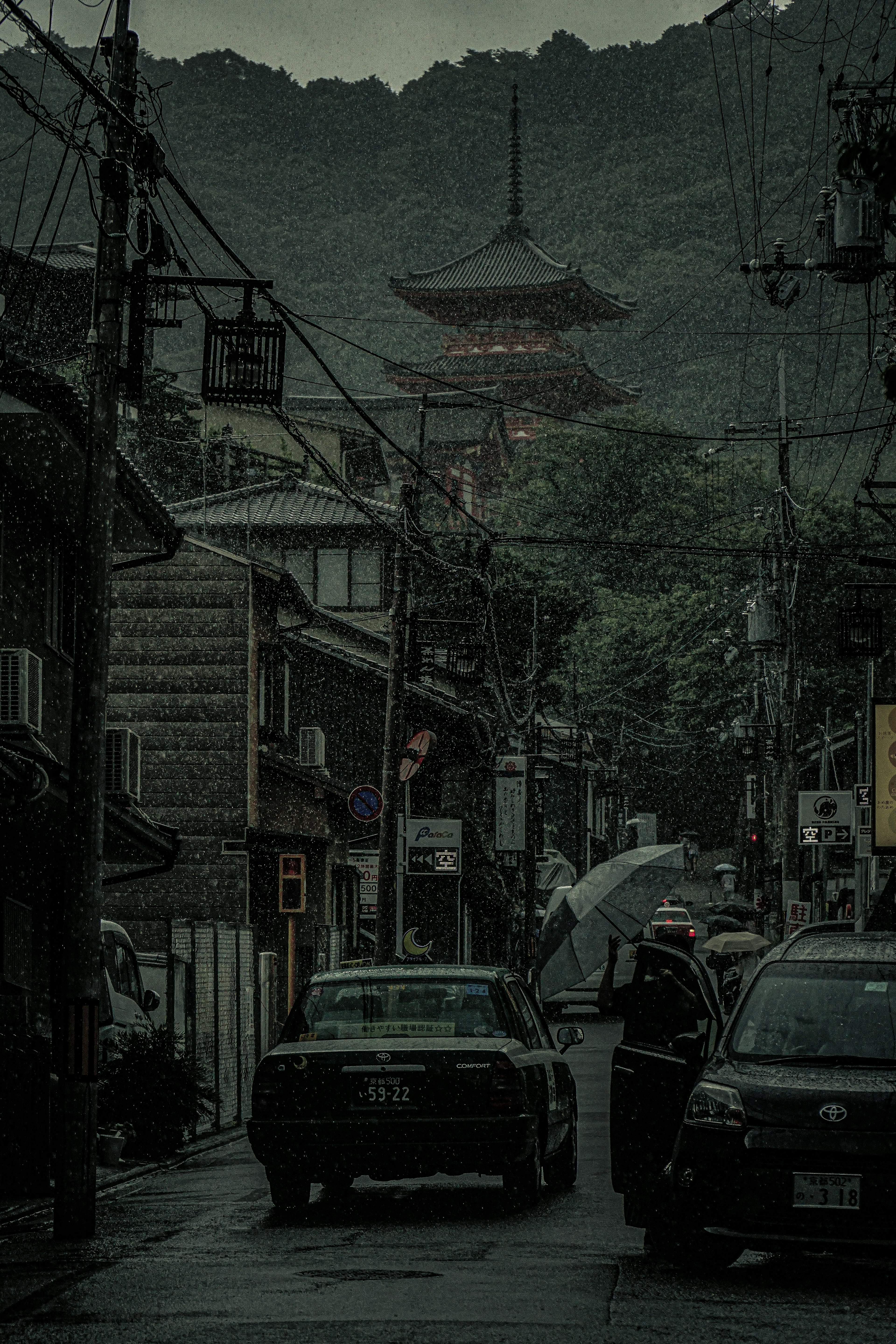 雨の中の古い街並みと山に囲まれた五重塔