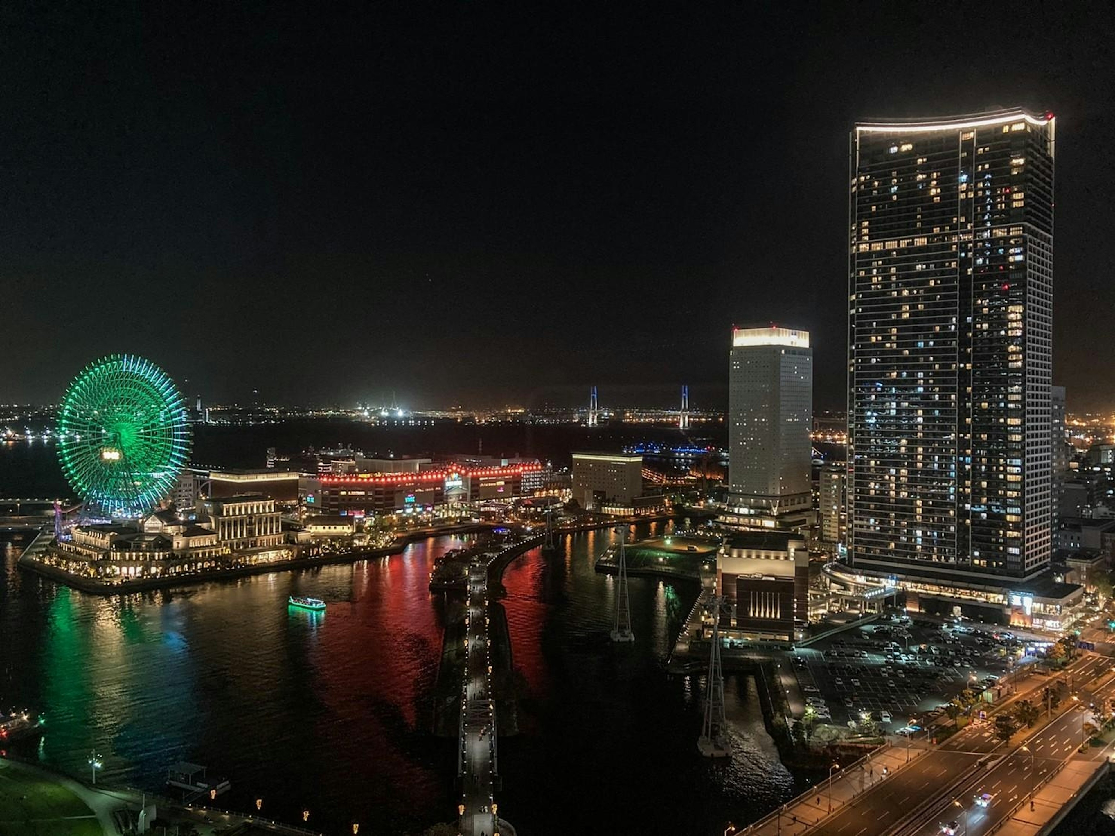 Stupenda vista notturna di un porto con grattacieli e una ruota panoramica illuminata