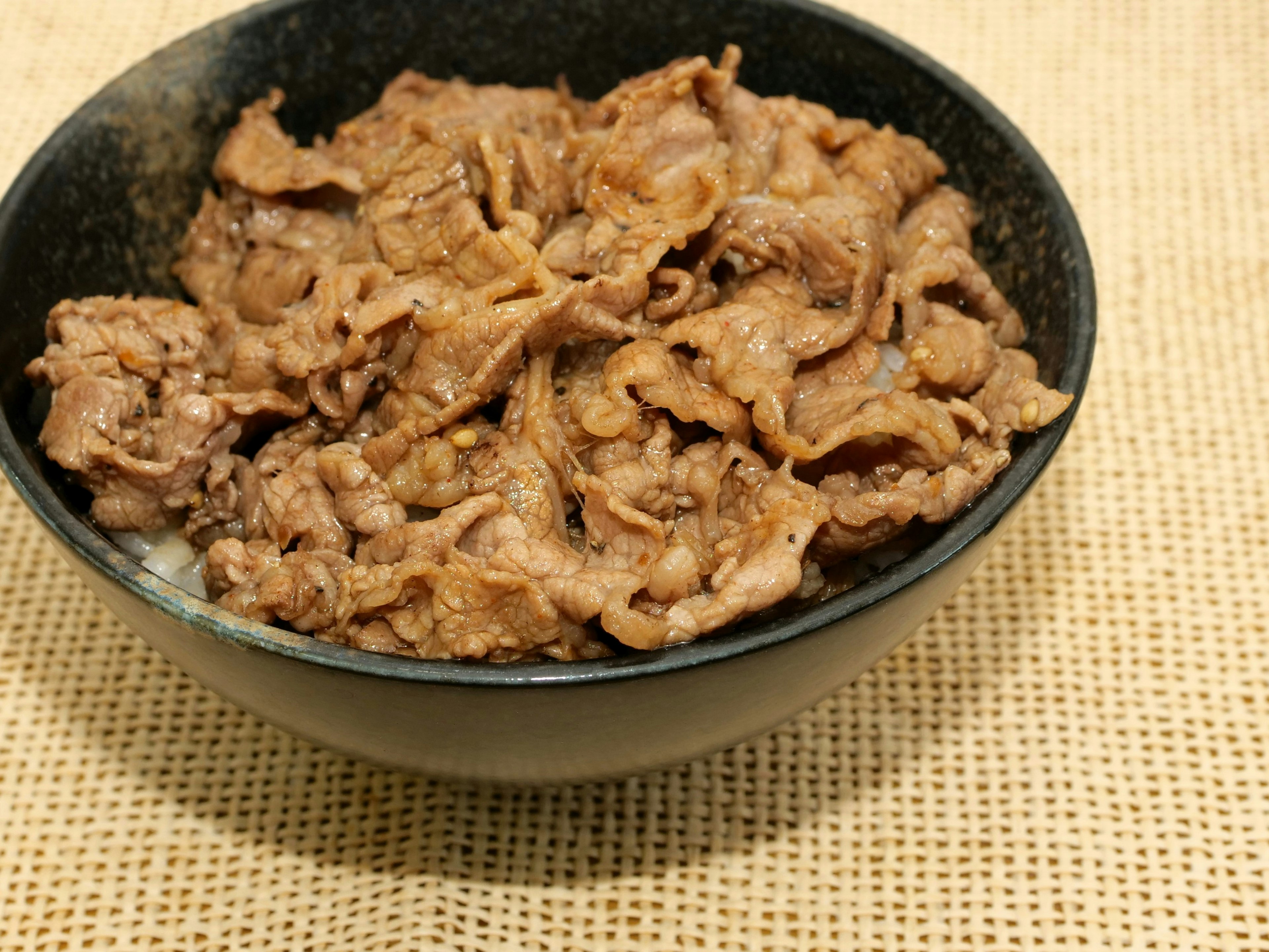 Thinly sliced meat dish in a black bowl