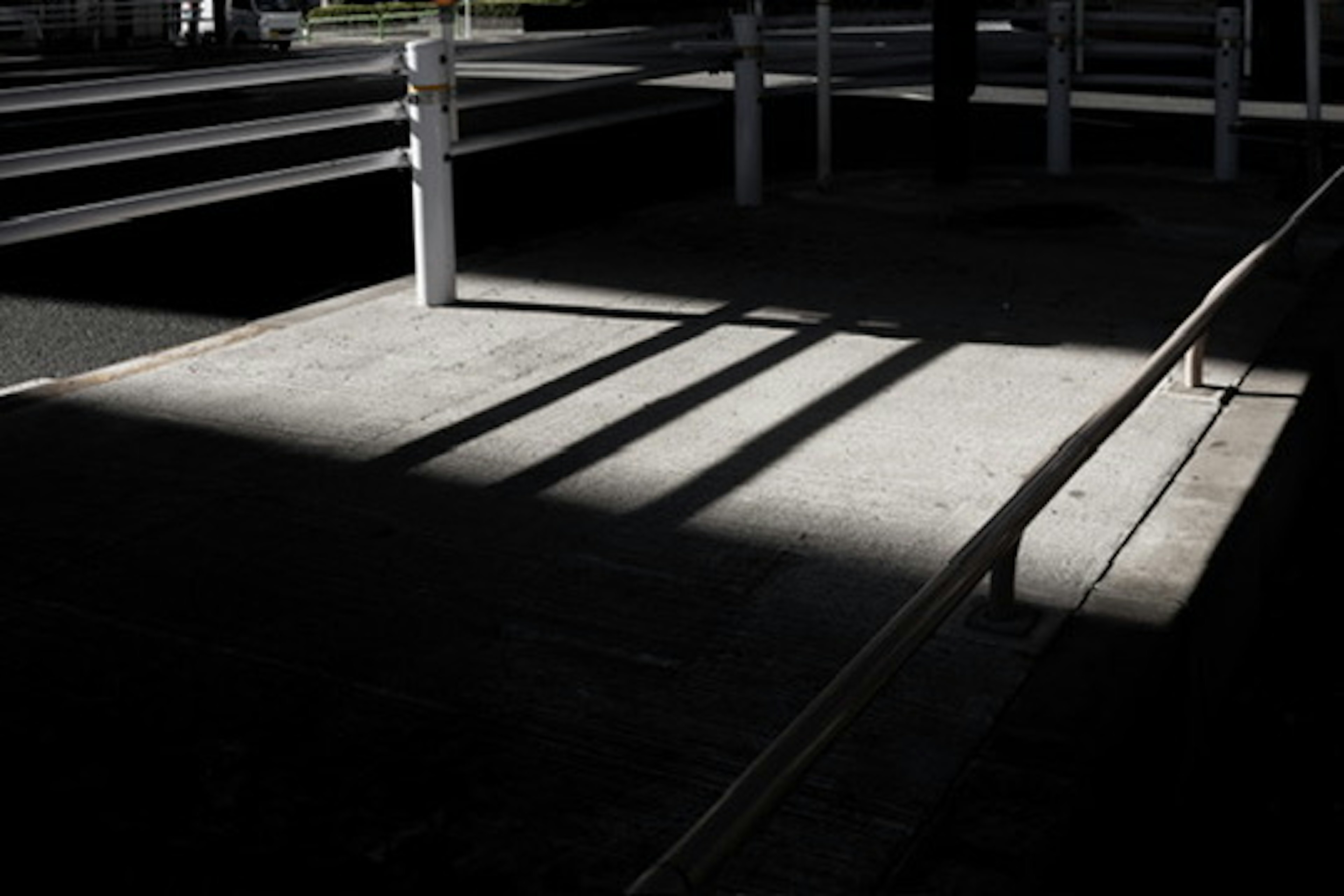 Suelo de concreto con fuerte contraste de sombras y luz con barandillas