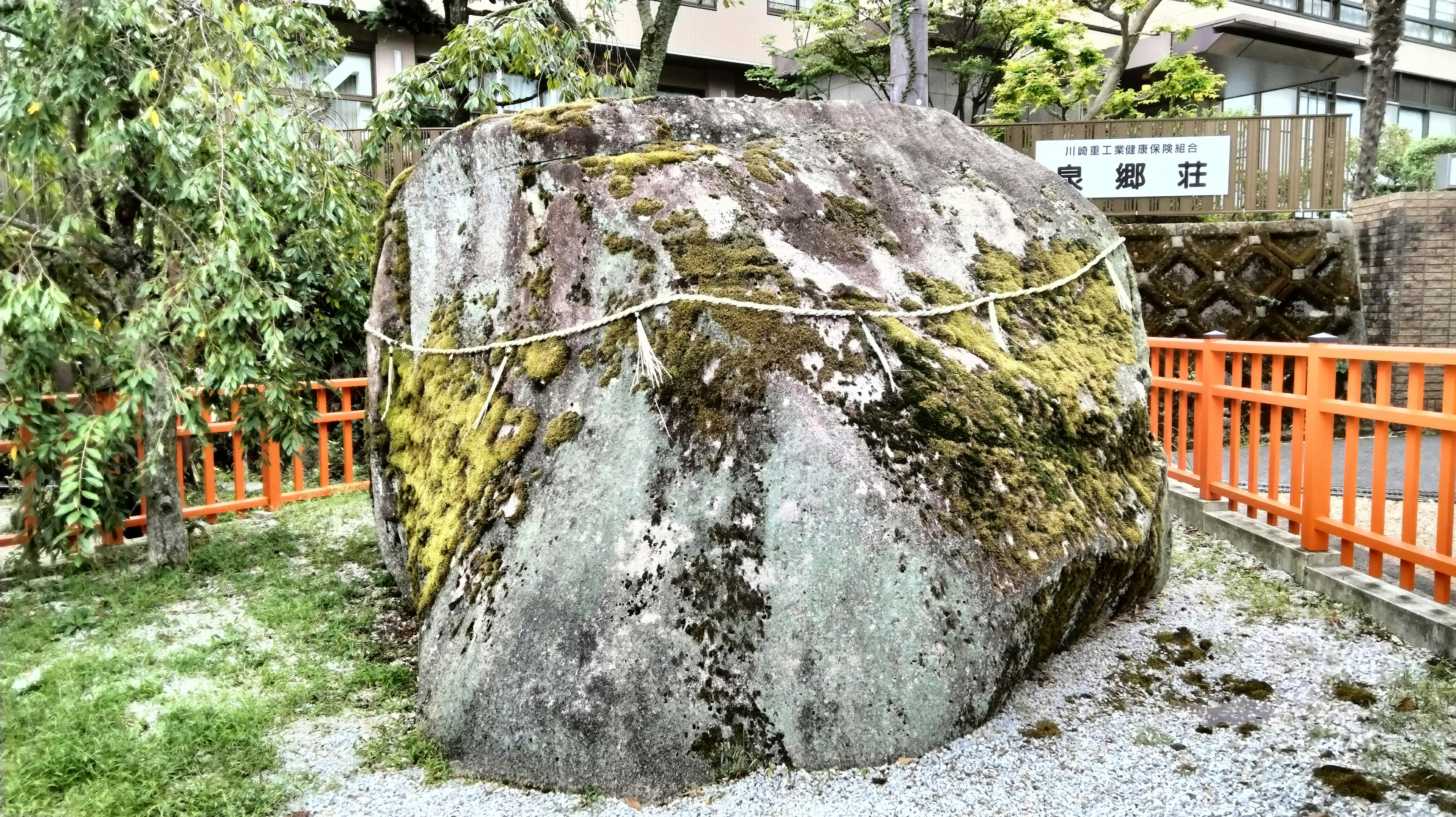 Gran roca cubierta de musgo rodeada de una cerca naranja