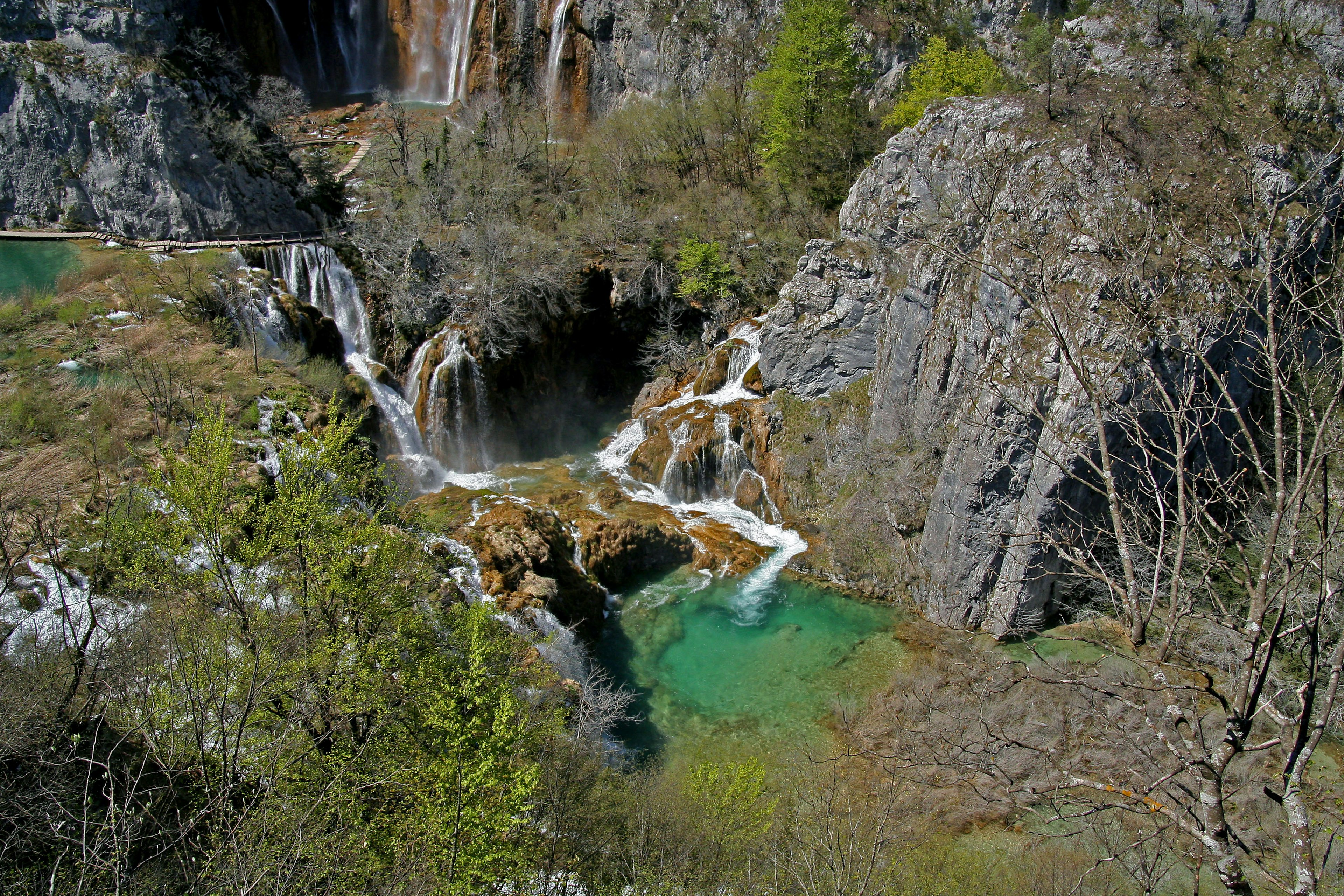 วิวทิวทัศน์ที่สวยงามของน้ำตกและบ่อน้ำสีเขียวมรกตที่ล้อมรอบด้วยภูเขาหิน