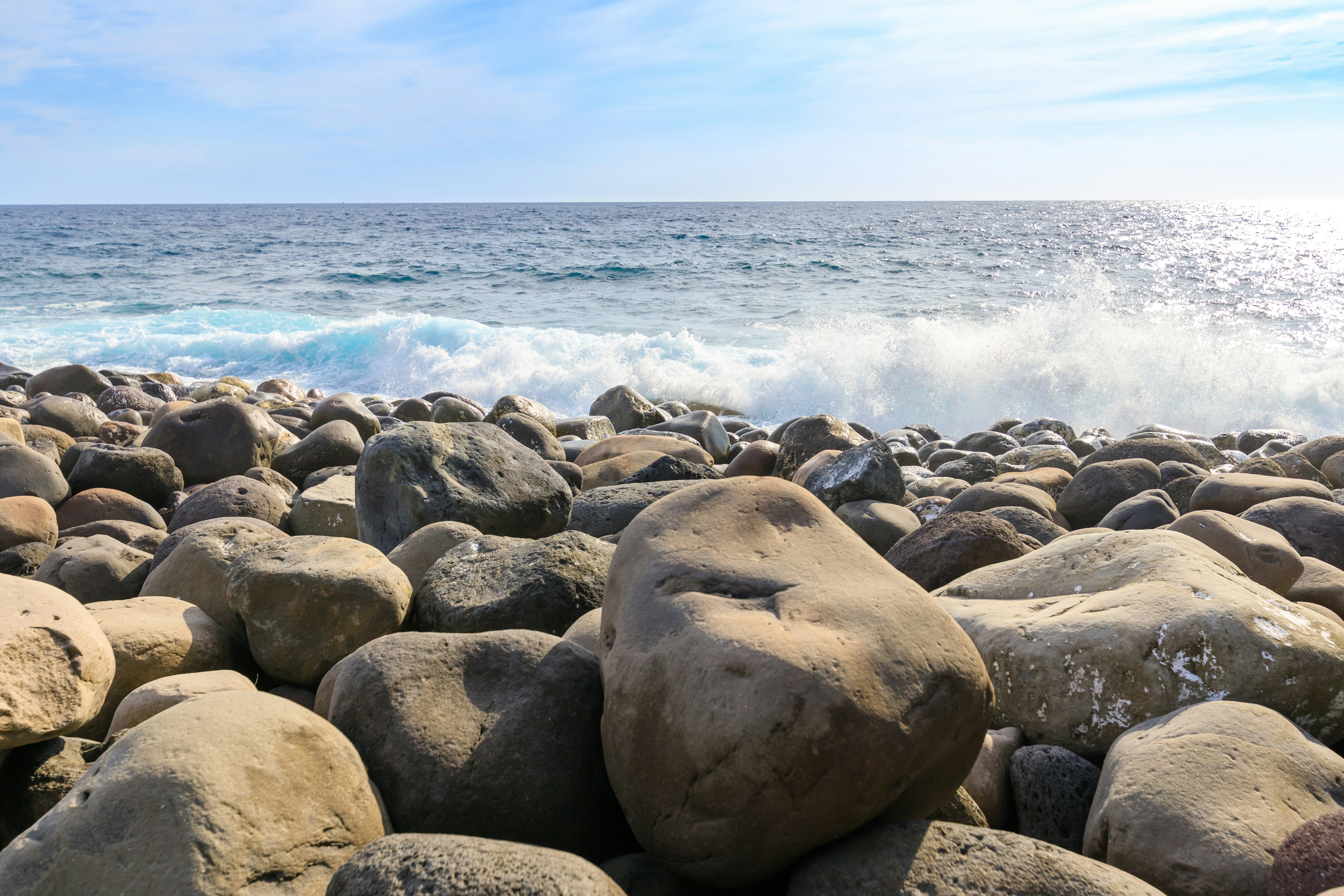 Pemandangan pantai dengan batu besar dan gelombang yang menghantam