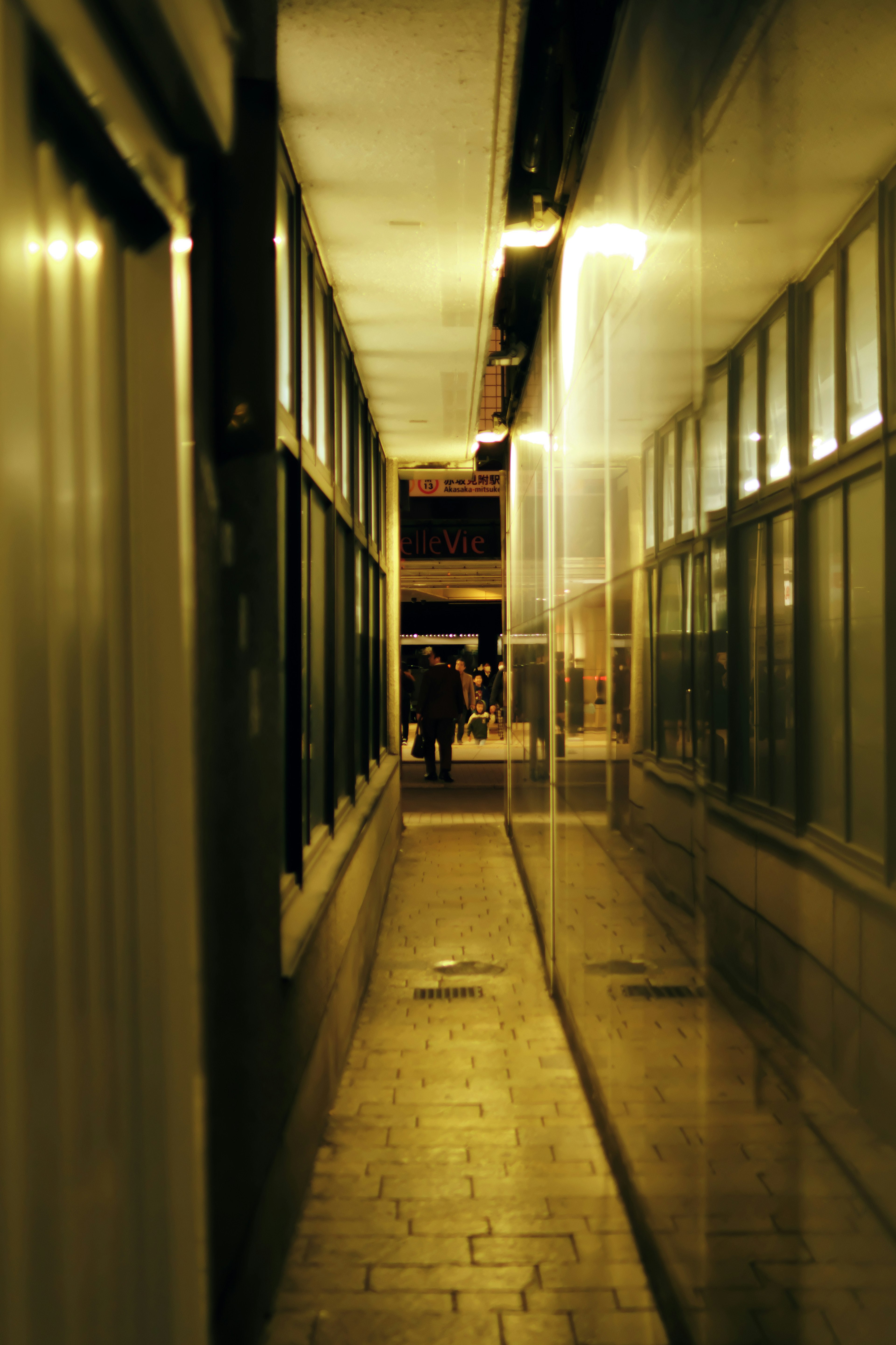 Narrow alley at night with glass walls and warm lighting