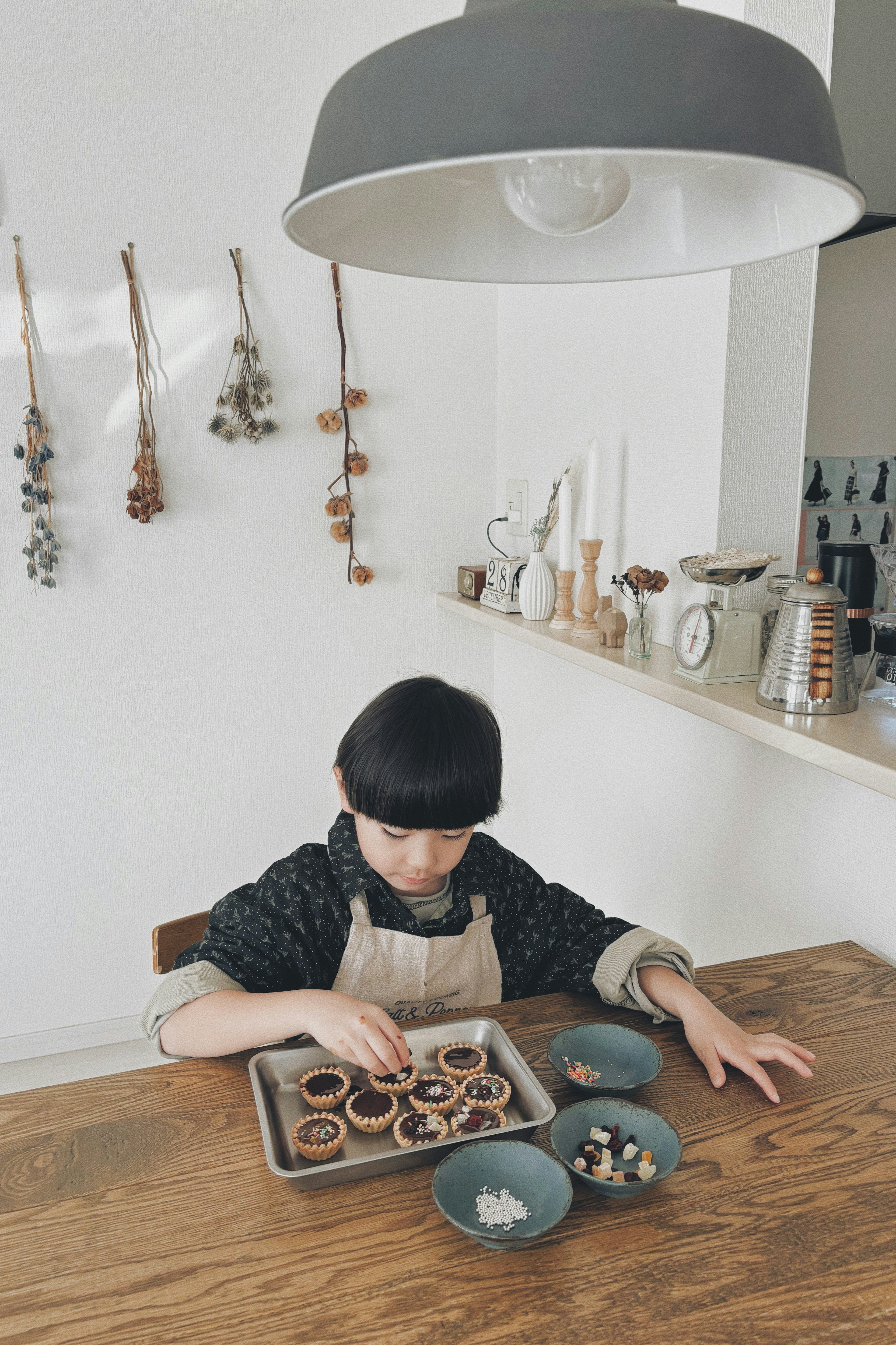 Bambino che prepara dolci su un tavolo di legno cucina luminosa con utensili e decorazioni