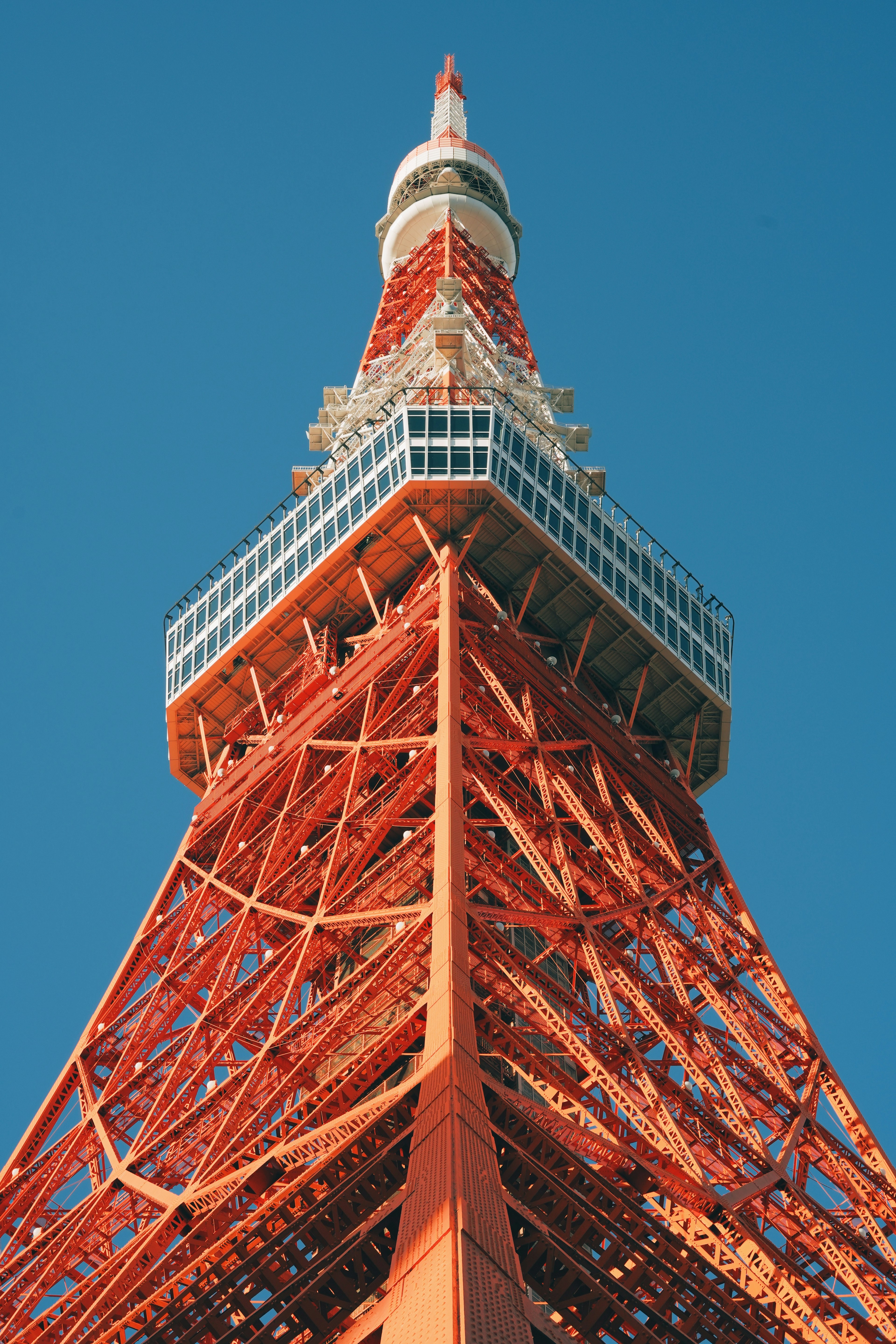 Image of Tokyo Tower viewed from below against a blue sky featuring an orange iron structure