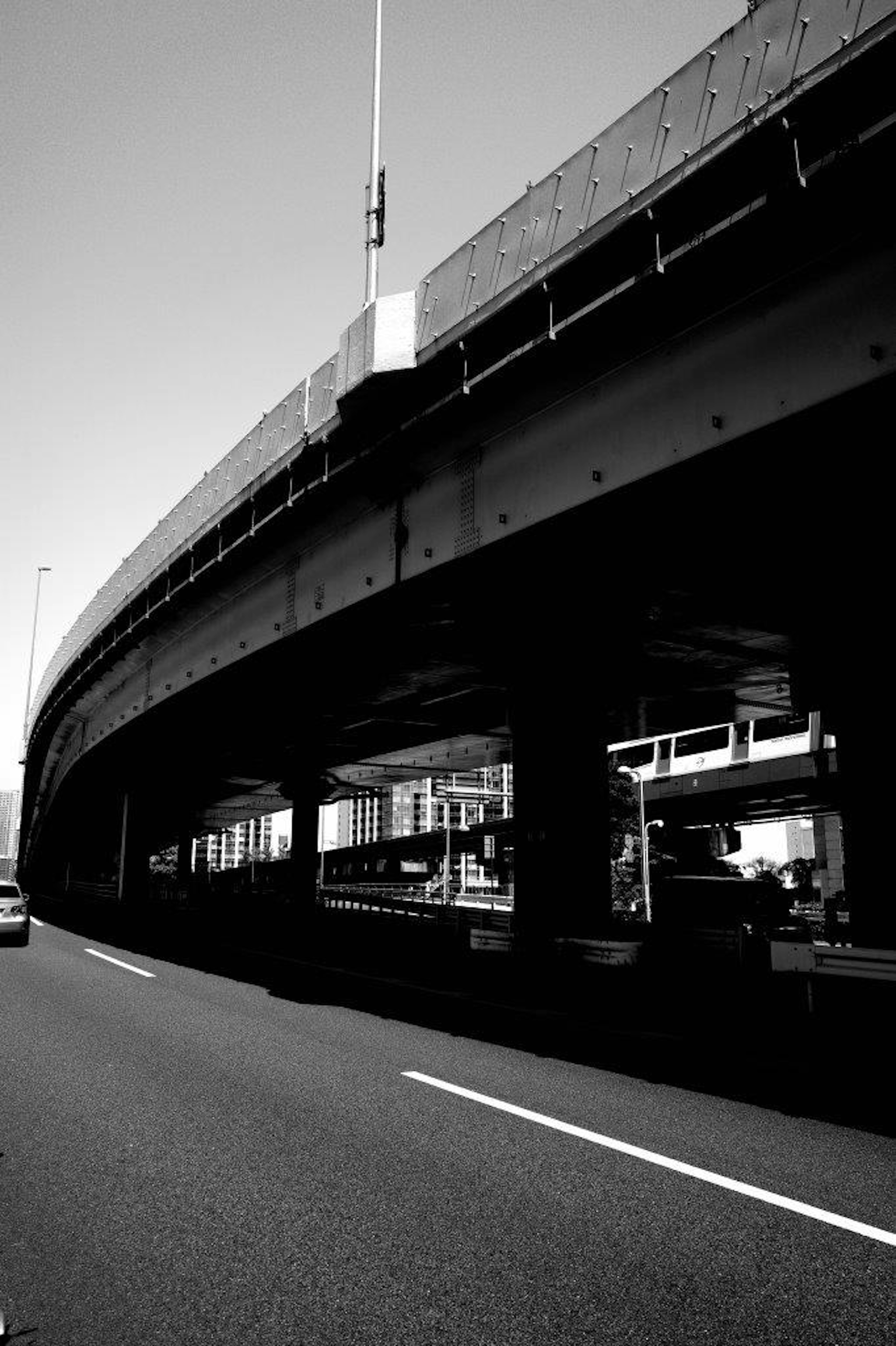 黒と白の高架道路の下を走る車と構造物の視覚