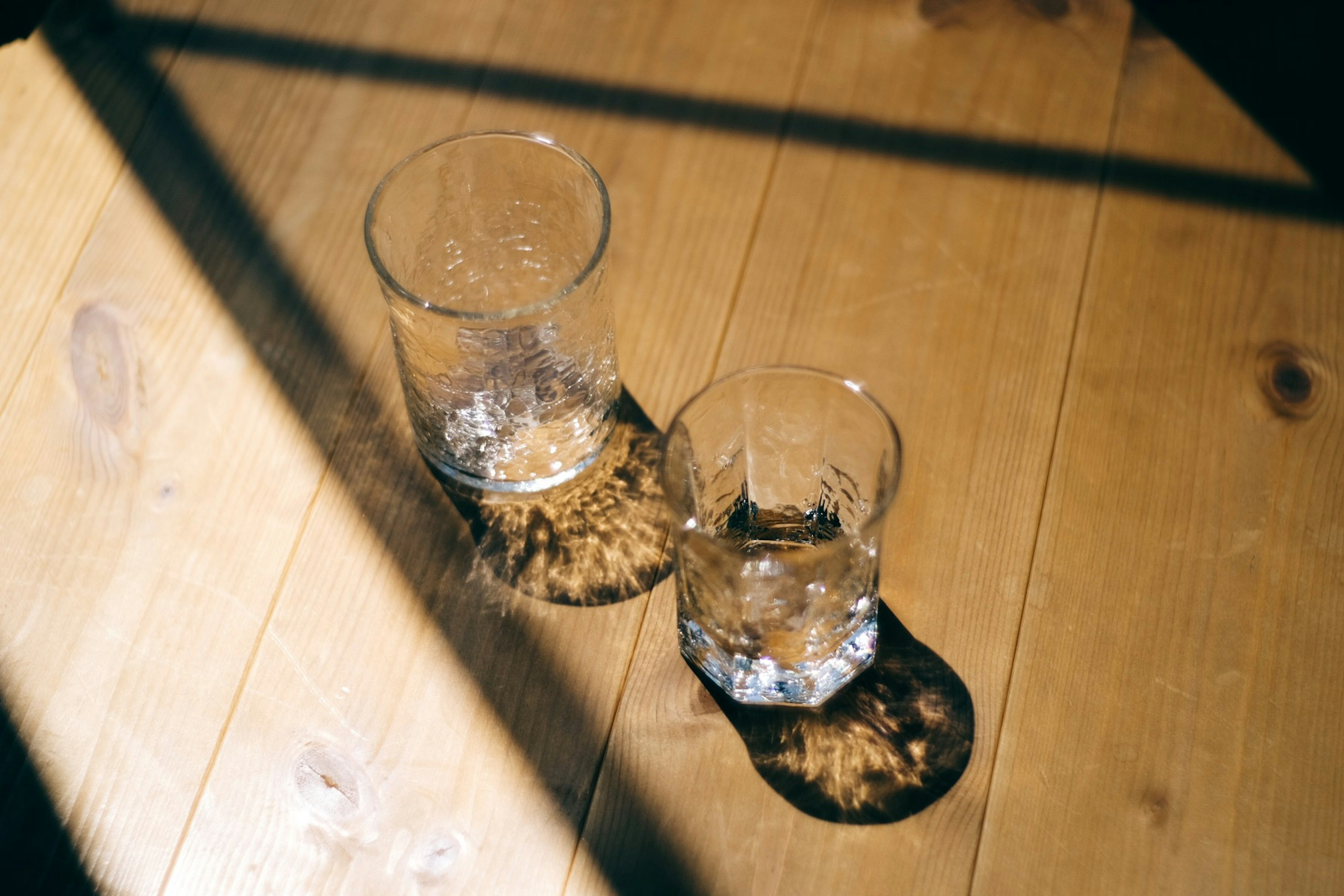 Zwei Gläser auf einem Holztisch mit Schatten