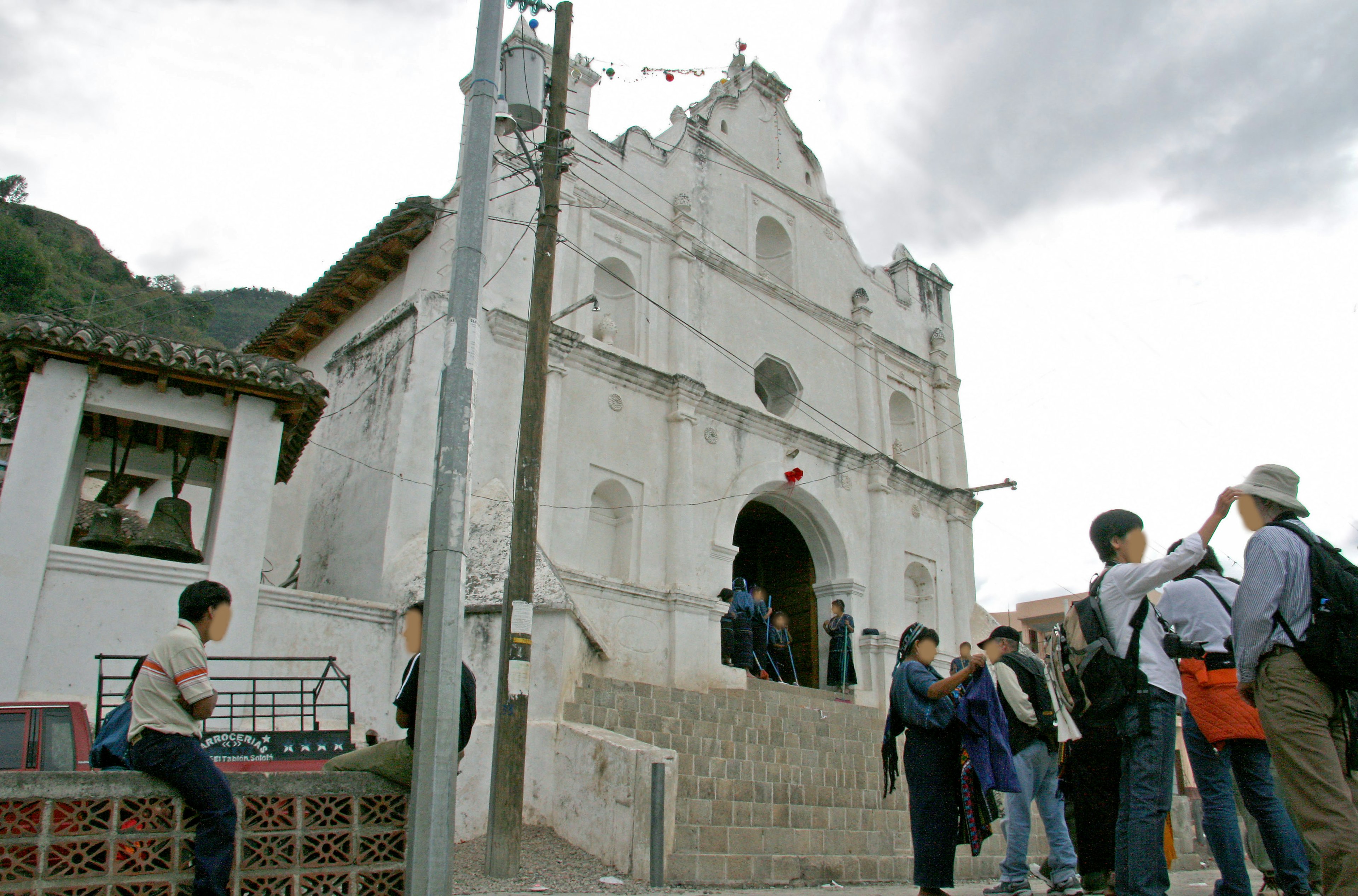 Turistas frente a una iglesia blanca con un niño sentado en los escalones