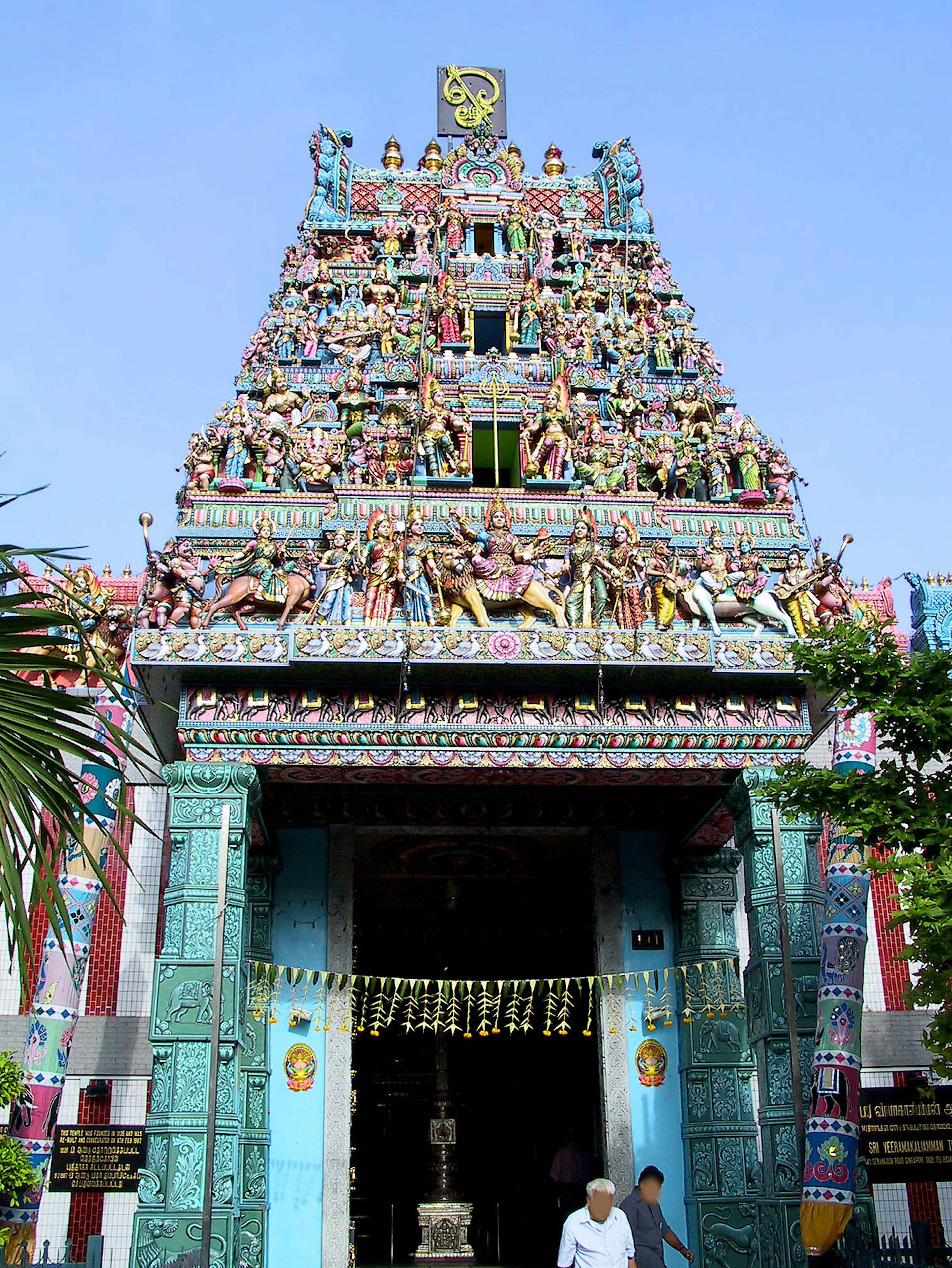 Entrance of a temple with colorful sculptures under a blue sky showcasing intricate architectural design