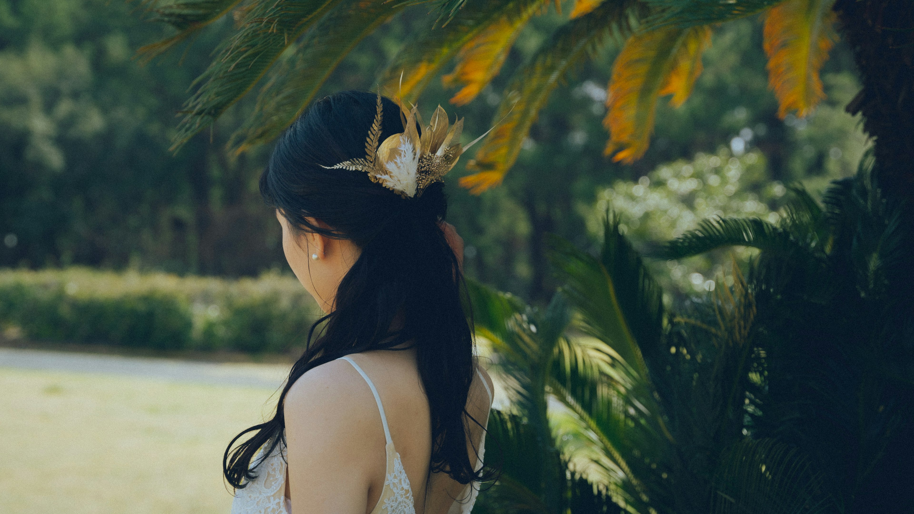 Une femme vue de dos portant un accessoire pour cheveux entourée de plantes vertes