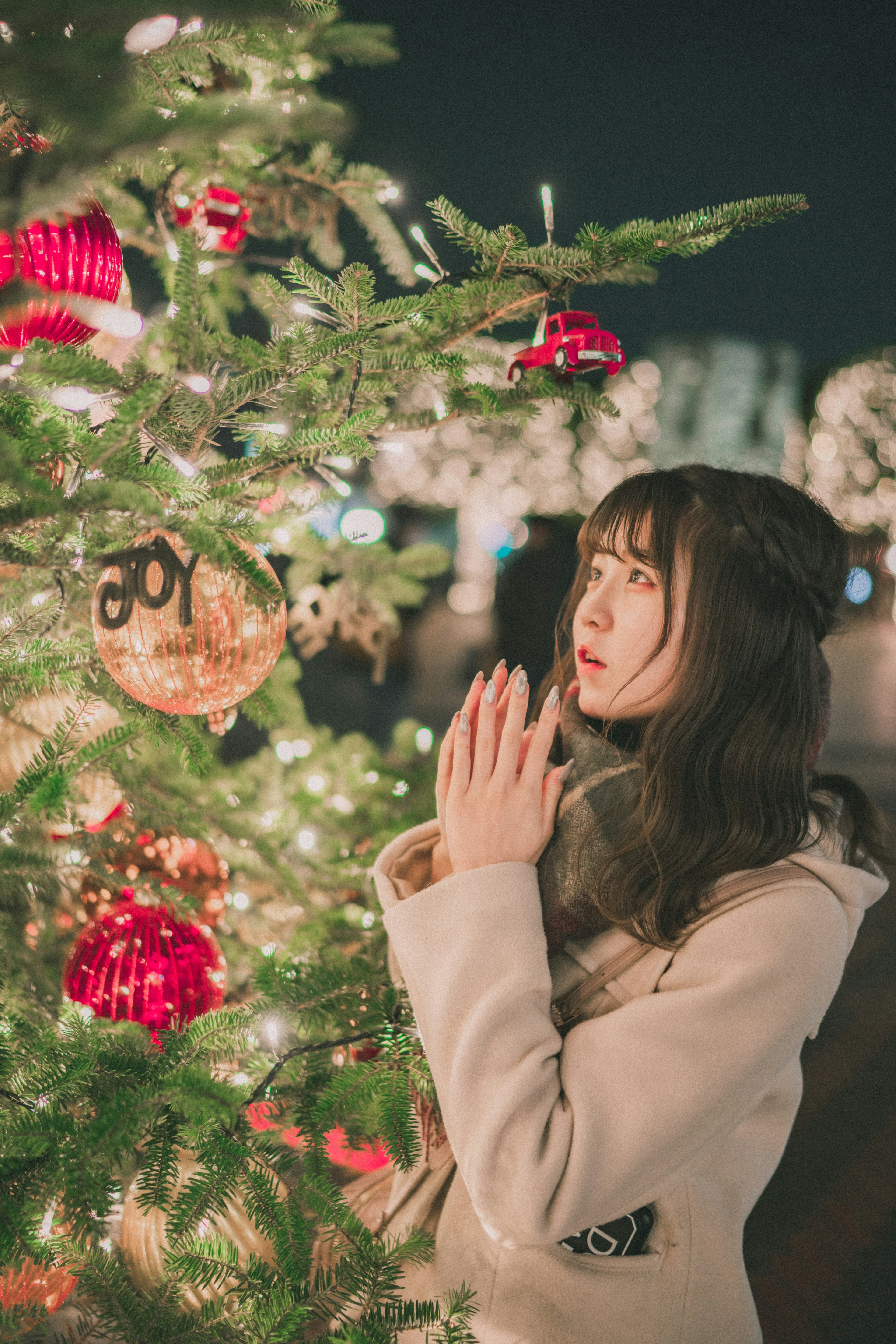 A woman praying in front of a Christmas tree