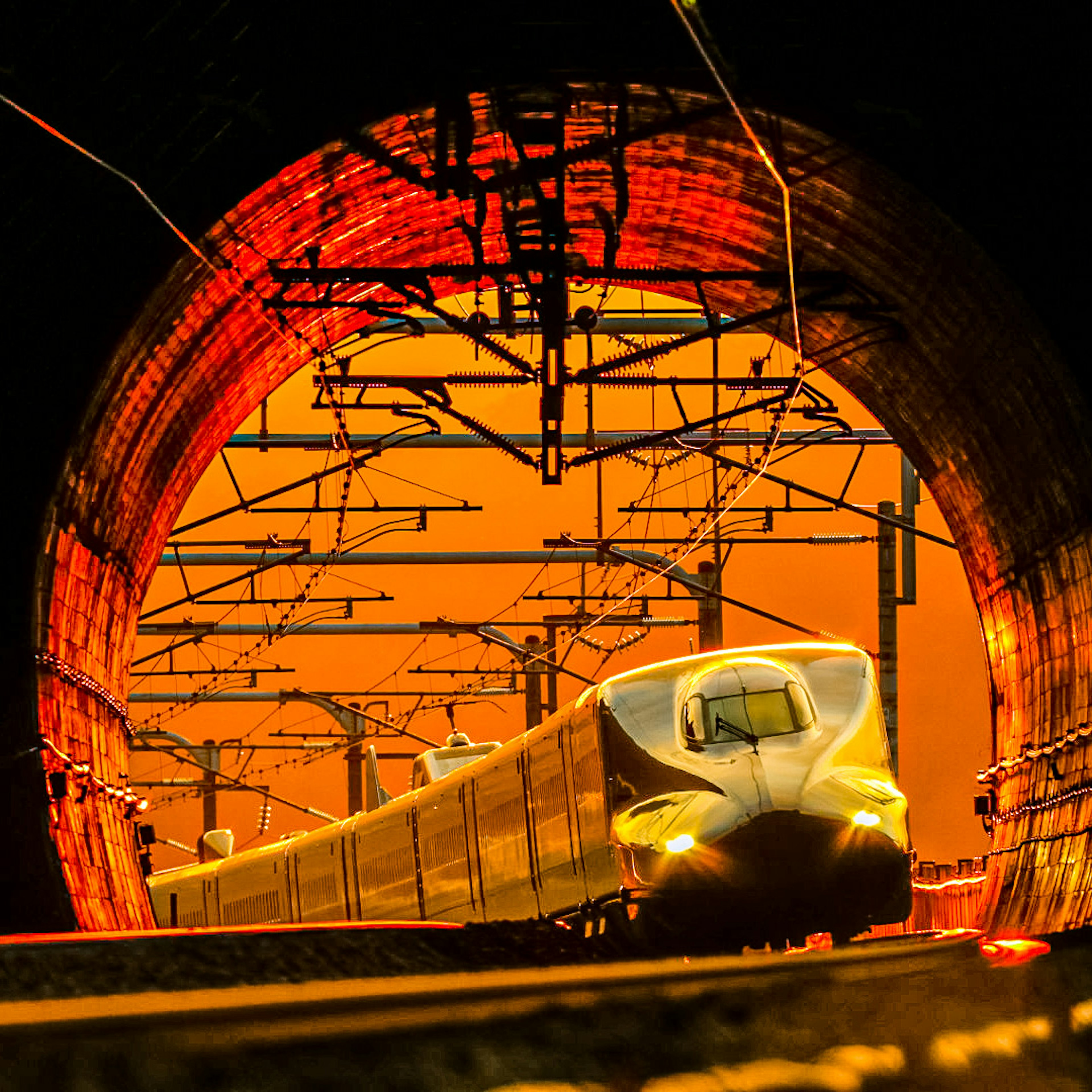 Shinkansen émergeant d'un tunnel avec un coucher de soleil en arrière-plan