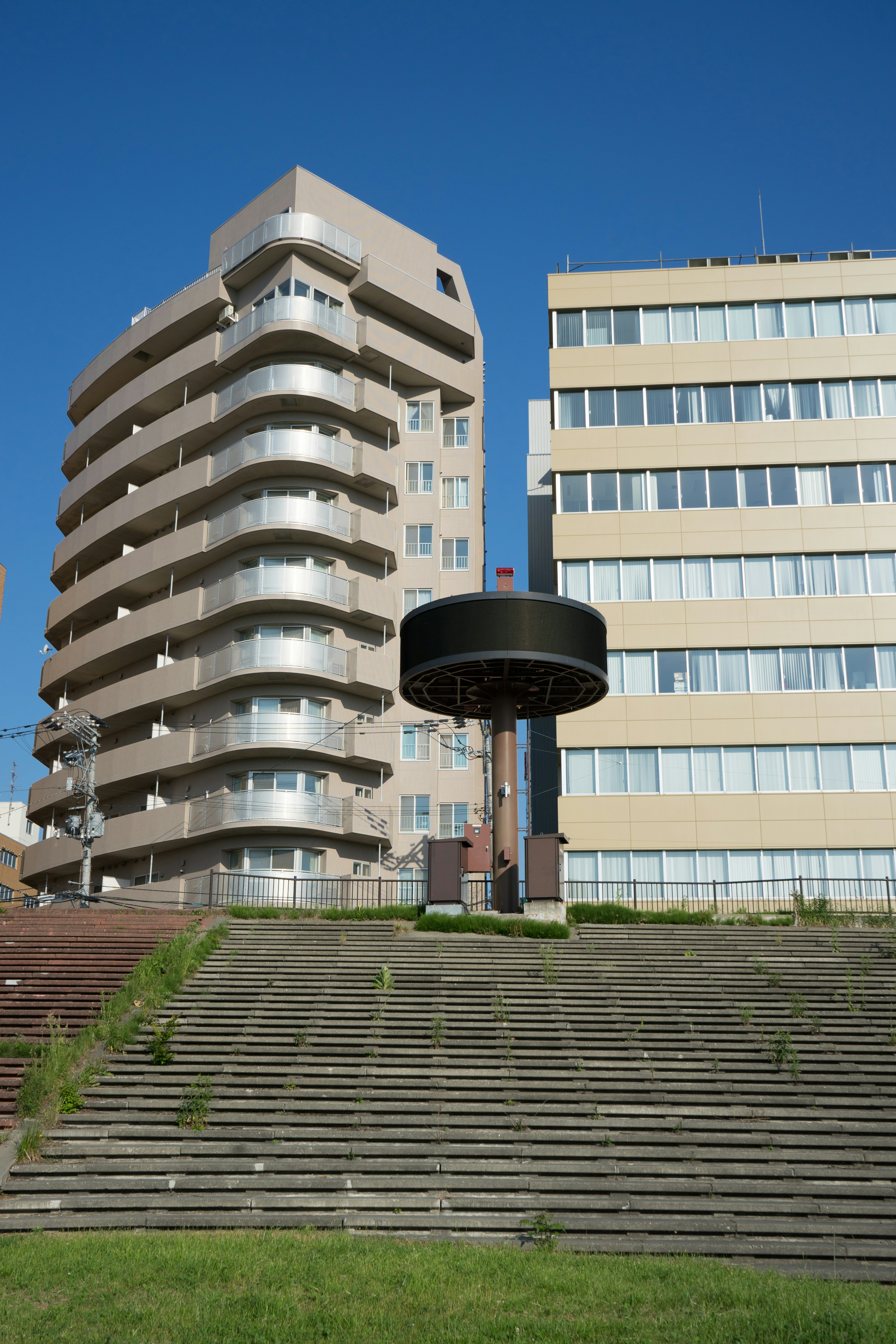 Struttura circolare nera davanti a un edificio alto e scale