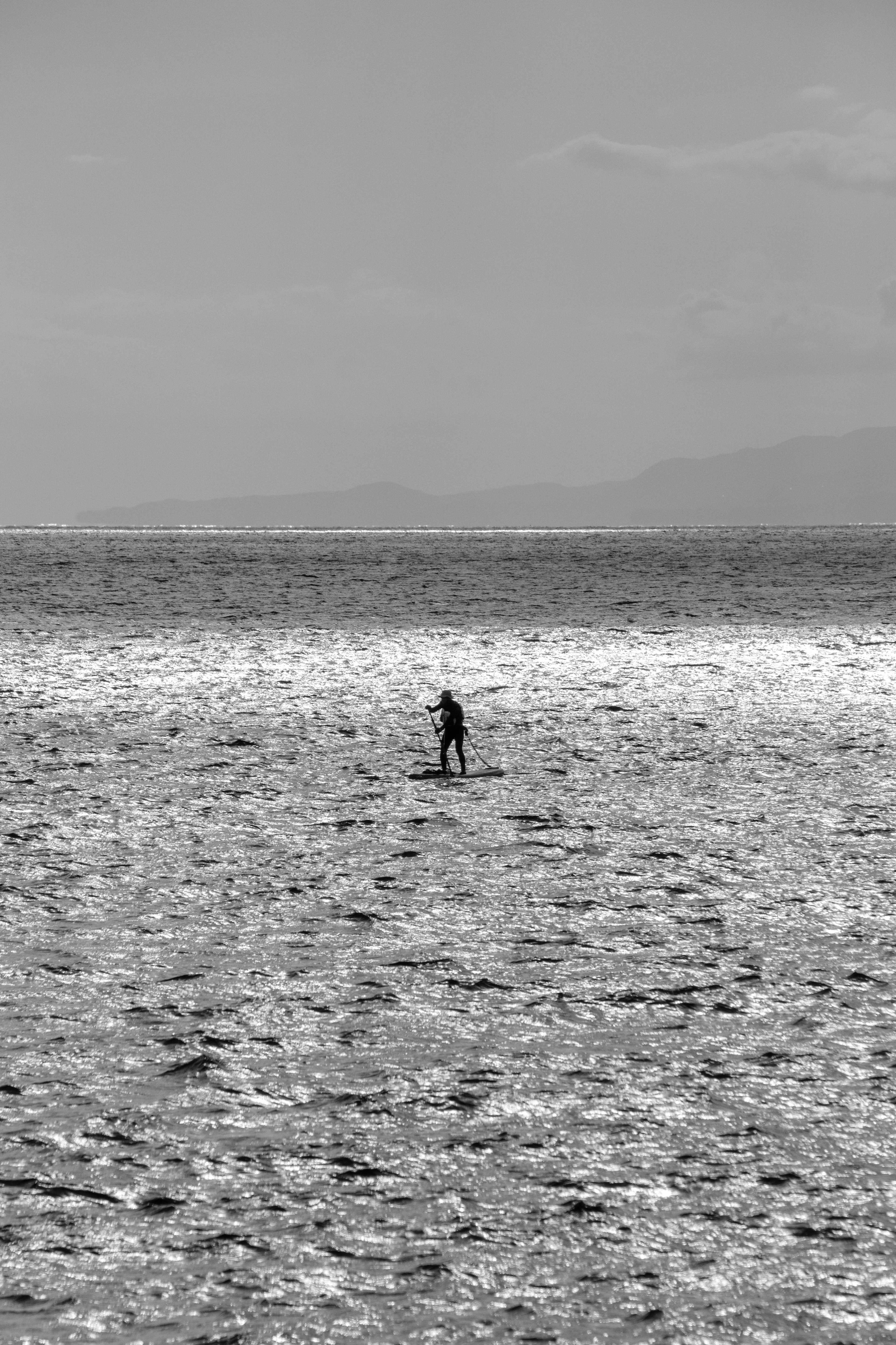 Une petite silhouette se tenant seule dans un paysage maritime en noir et blanc