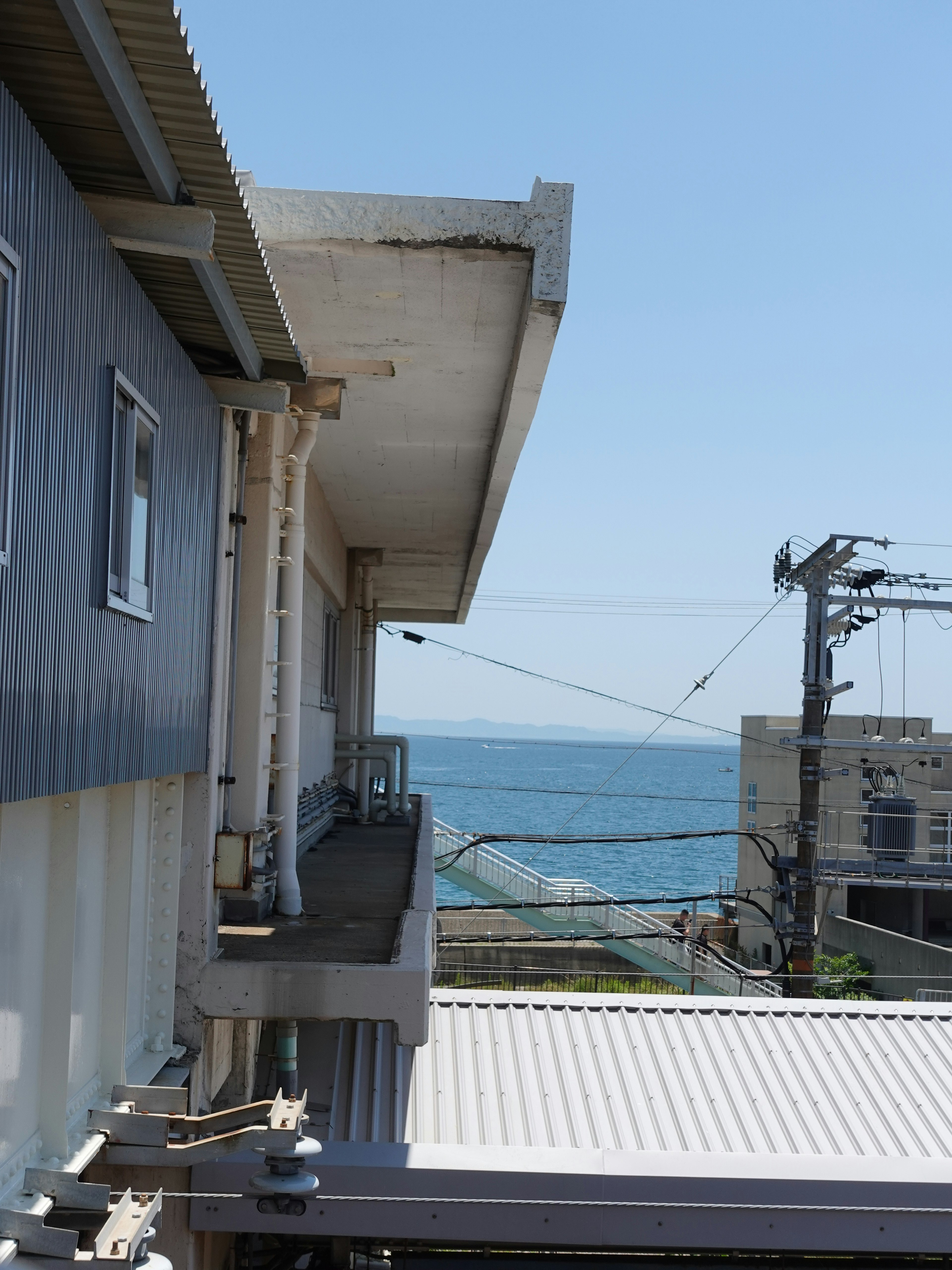 View of a building balcony overlooking the sea with power lines