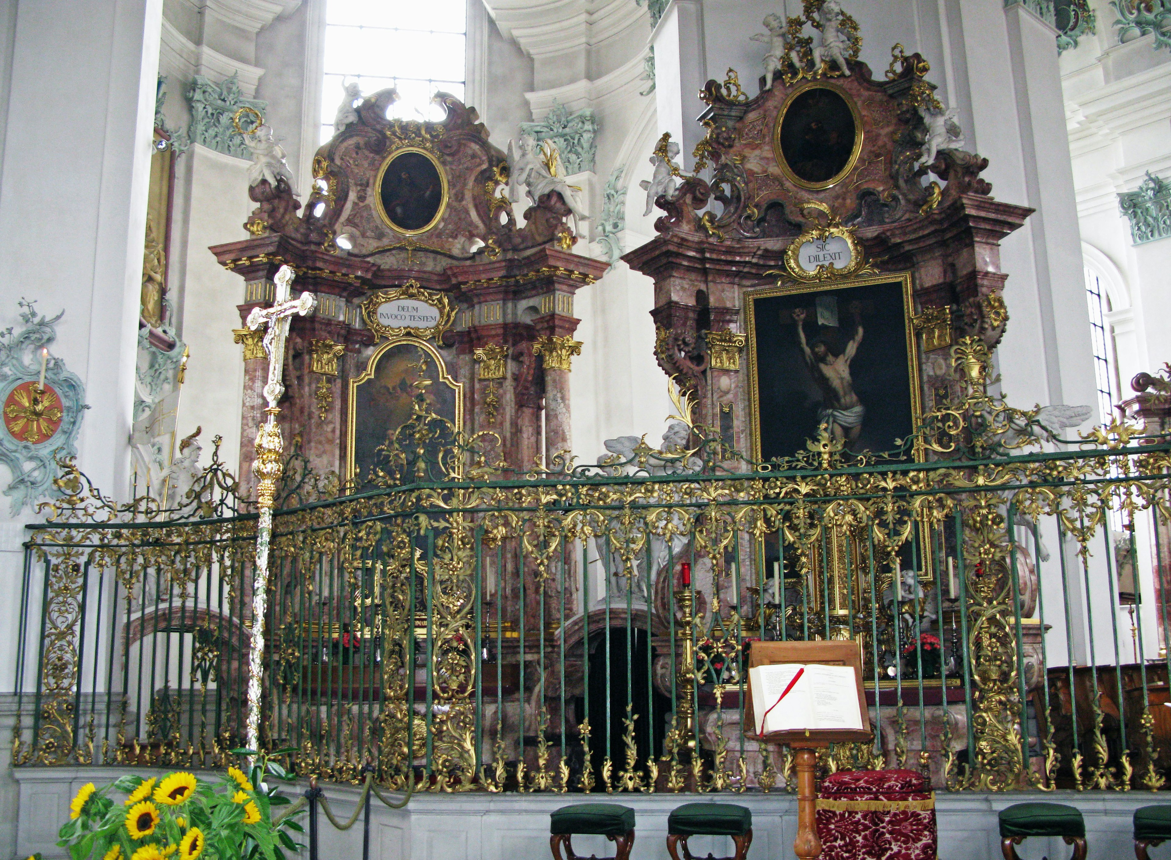 Interior de una iglesia con altares ornamentados y barandilla de metal intrincada