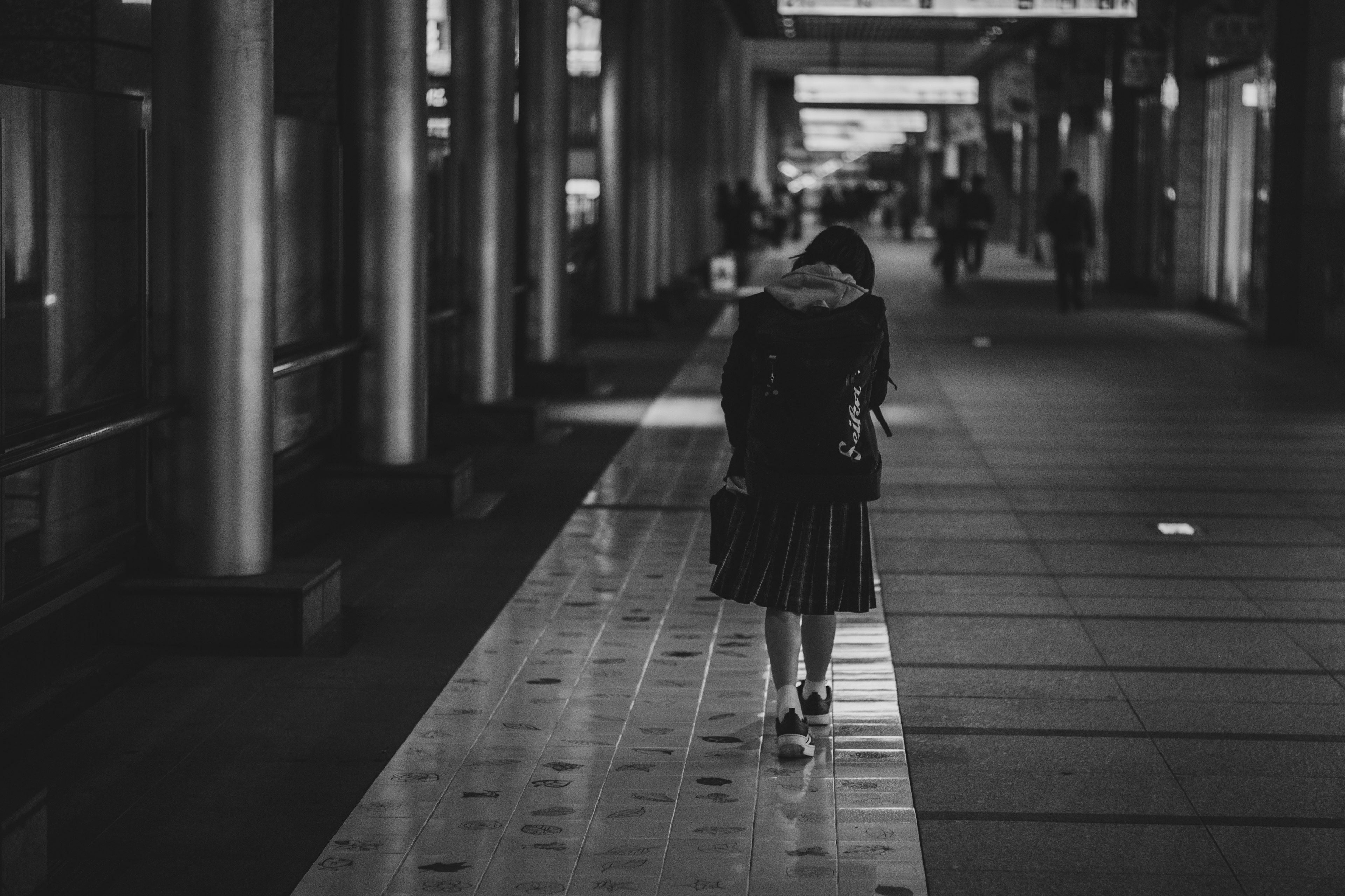 Une femme marchant seule dans une scène urbaine en noir et blanc