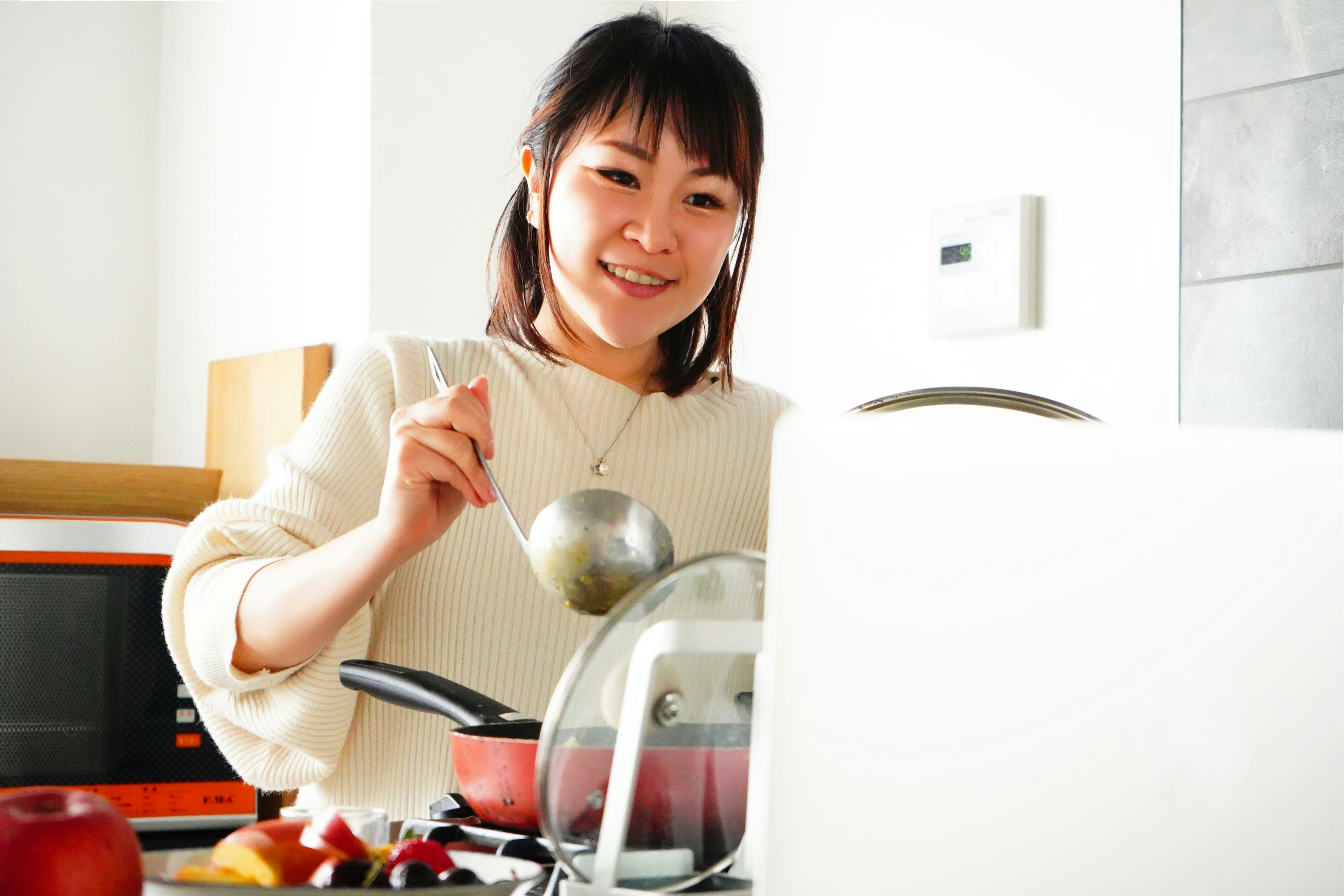 Wanita memasak di dapur tersenyum saat mengaduk sup