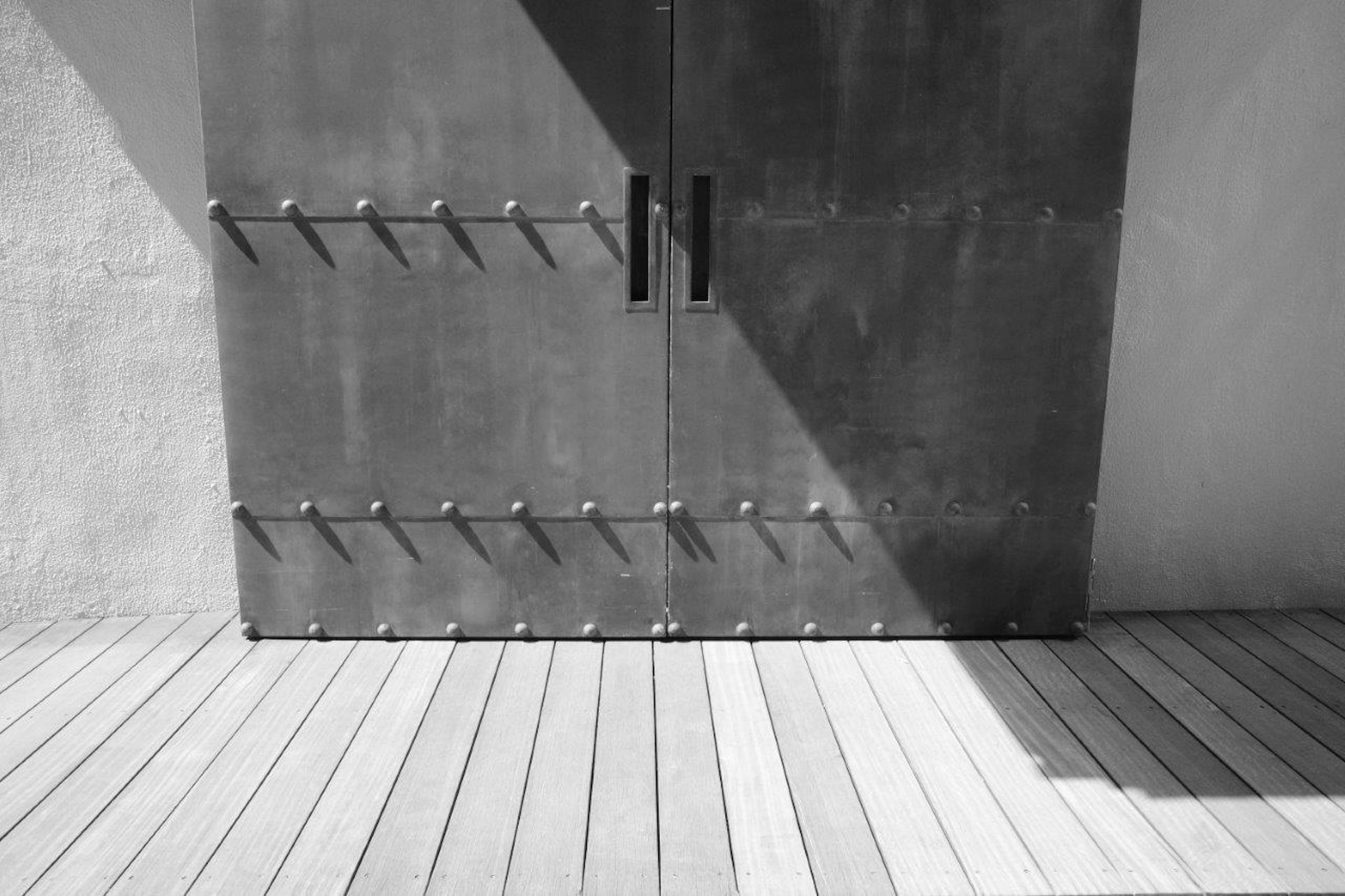 Photo of a metal door with handles and wooden flooring in a minimalist setting