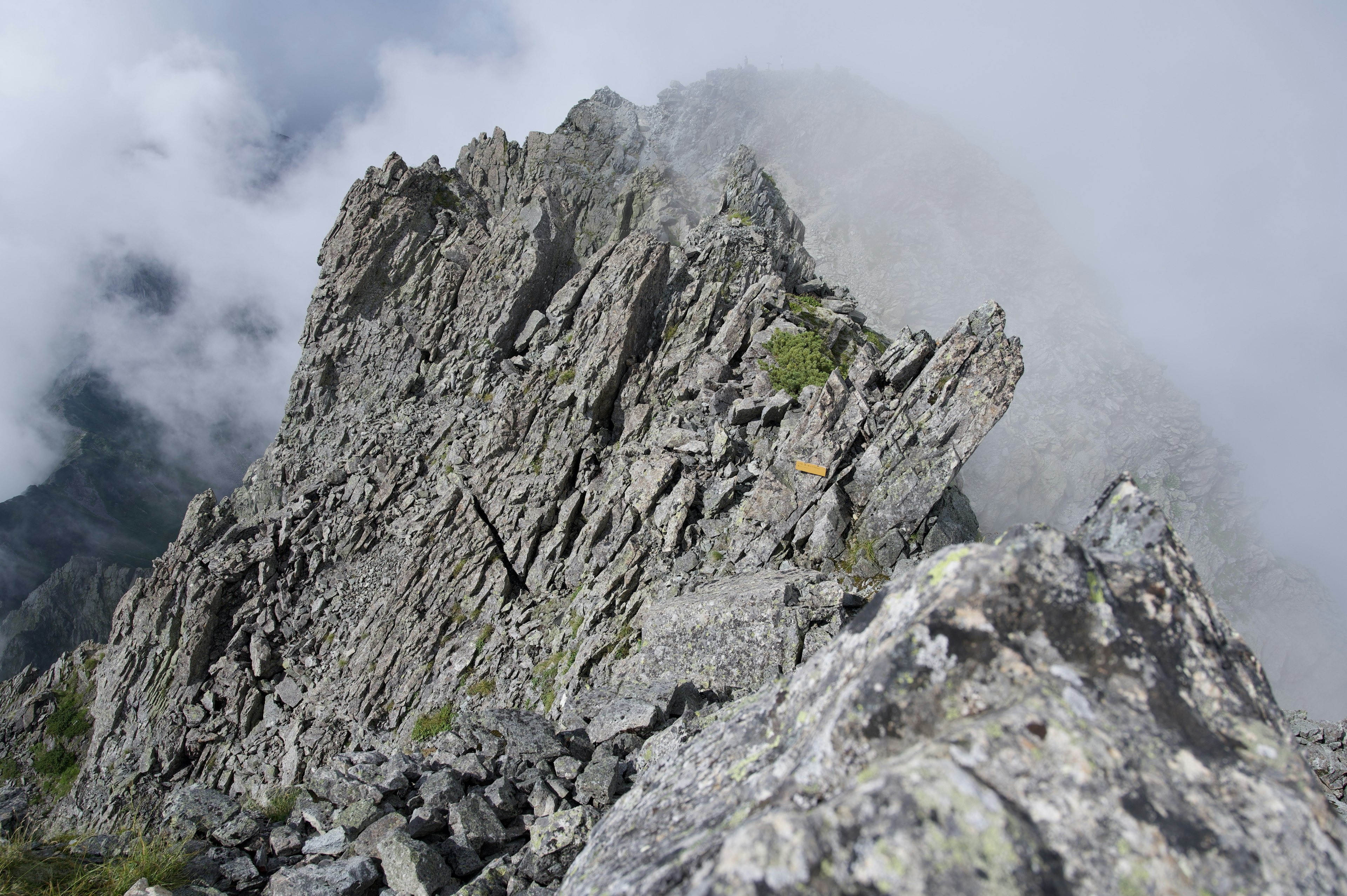 Pico de montaña escarpado con superficie rocosa y nubes alrededor