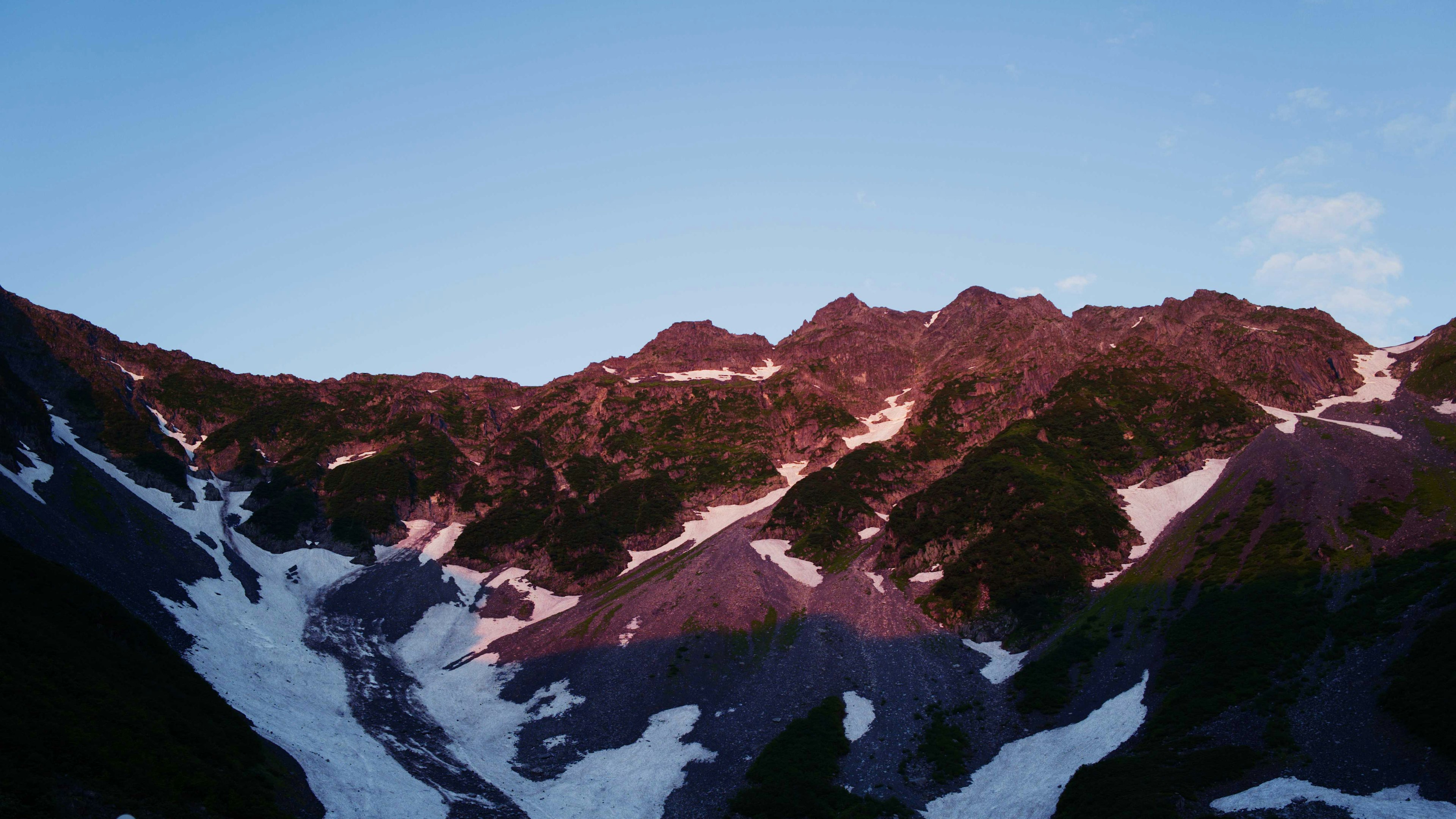 Vista escénica de montañas cubiertas de nieve iluminadas por el atardecer