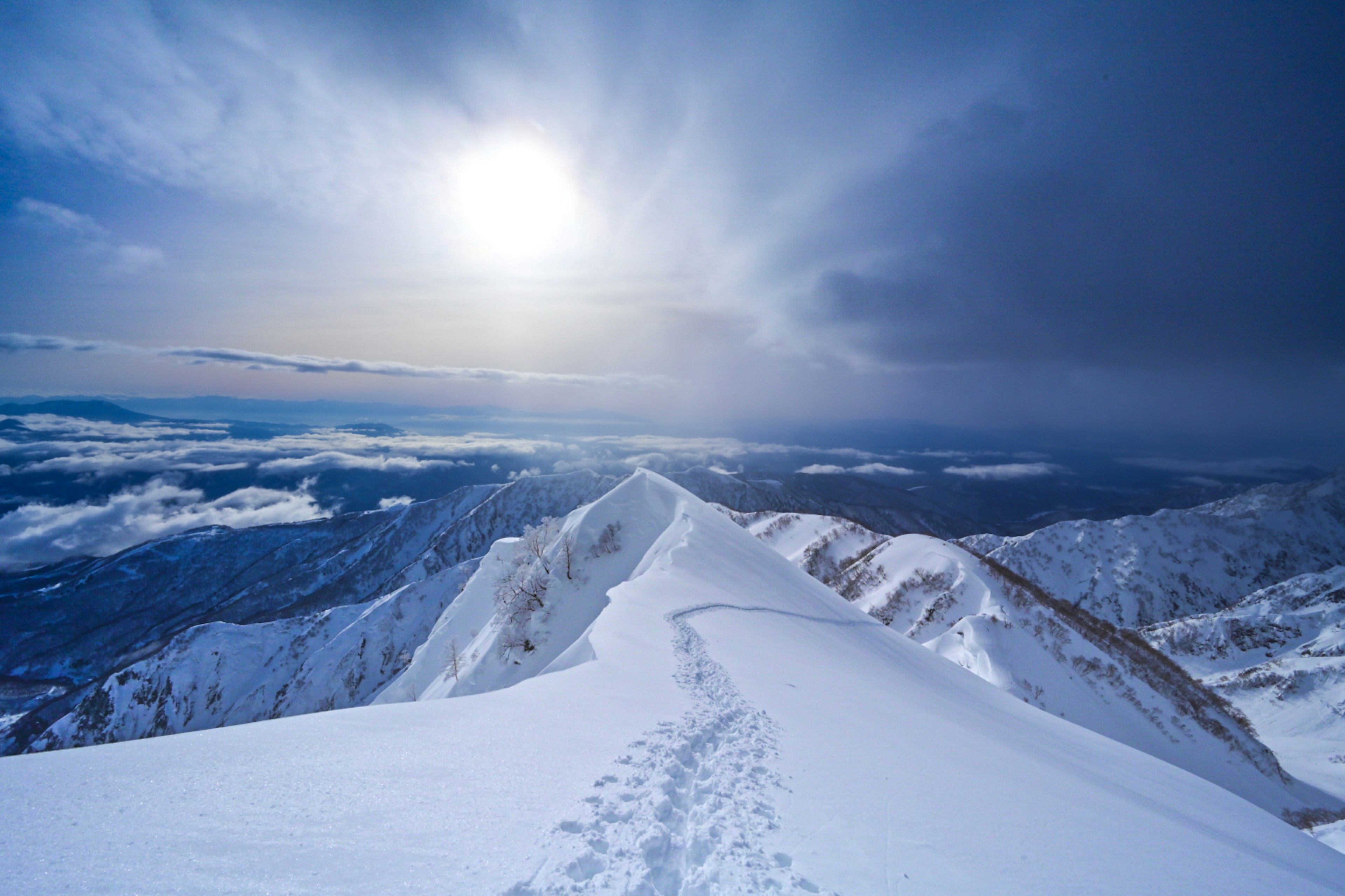 Schneebedeckter Berggipfel mit hellem Sonnenlicht und blauem Himmel