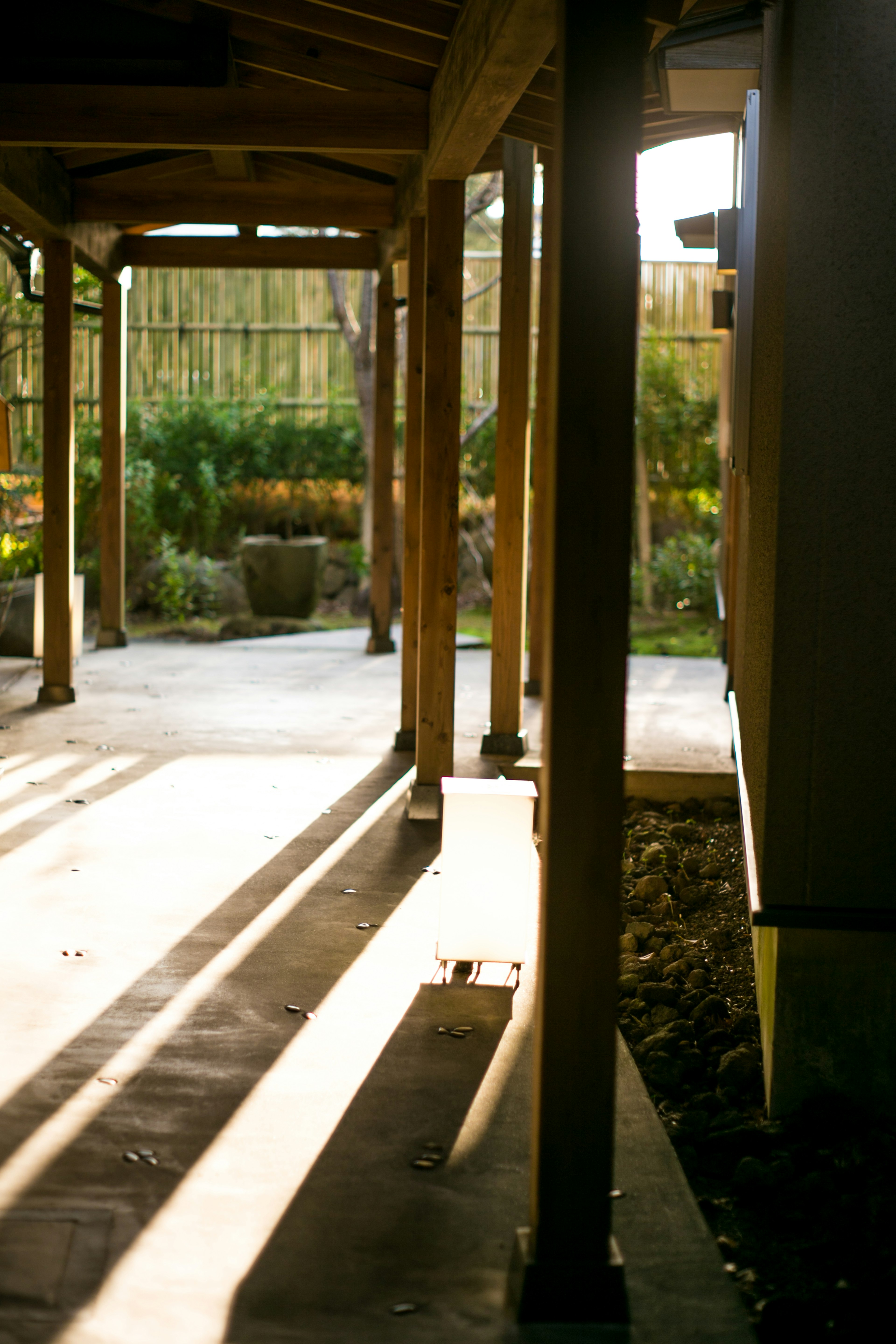 Foto de un pasillo con columnas de madera luz solar filtrándose creando sombras