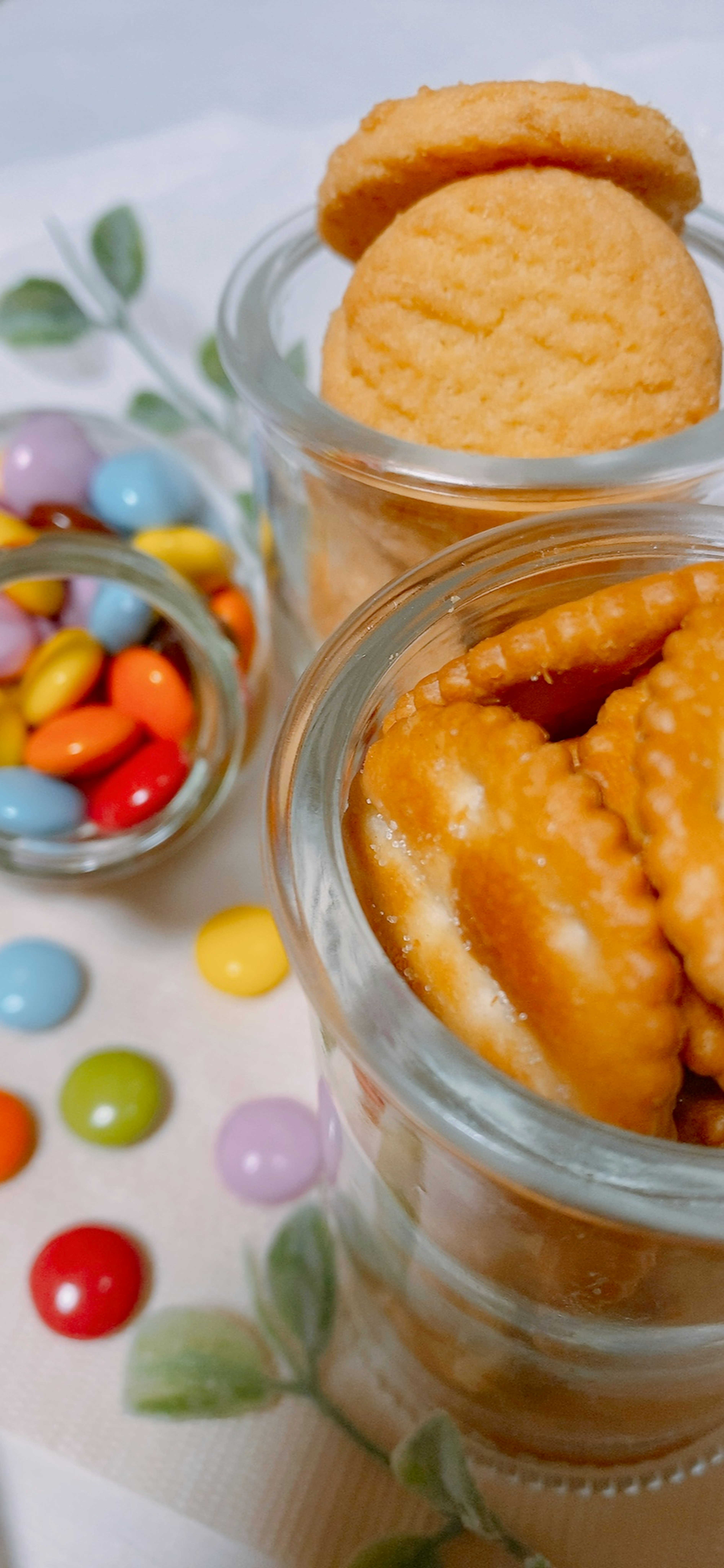 Biscuits in glass jars with colorful candies in the background